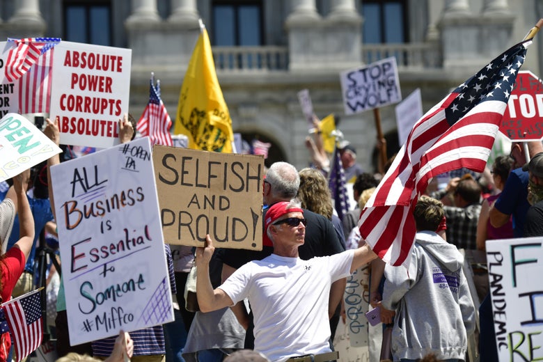 Demonstrators outside the Pennsylvania Capitol Building wave flags and signs that oppose COVID-related business closures.