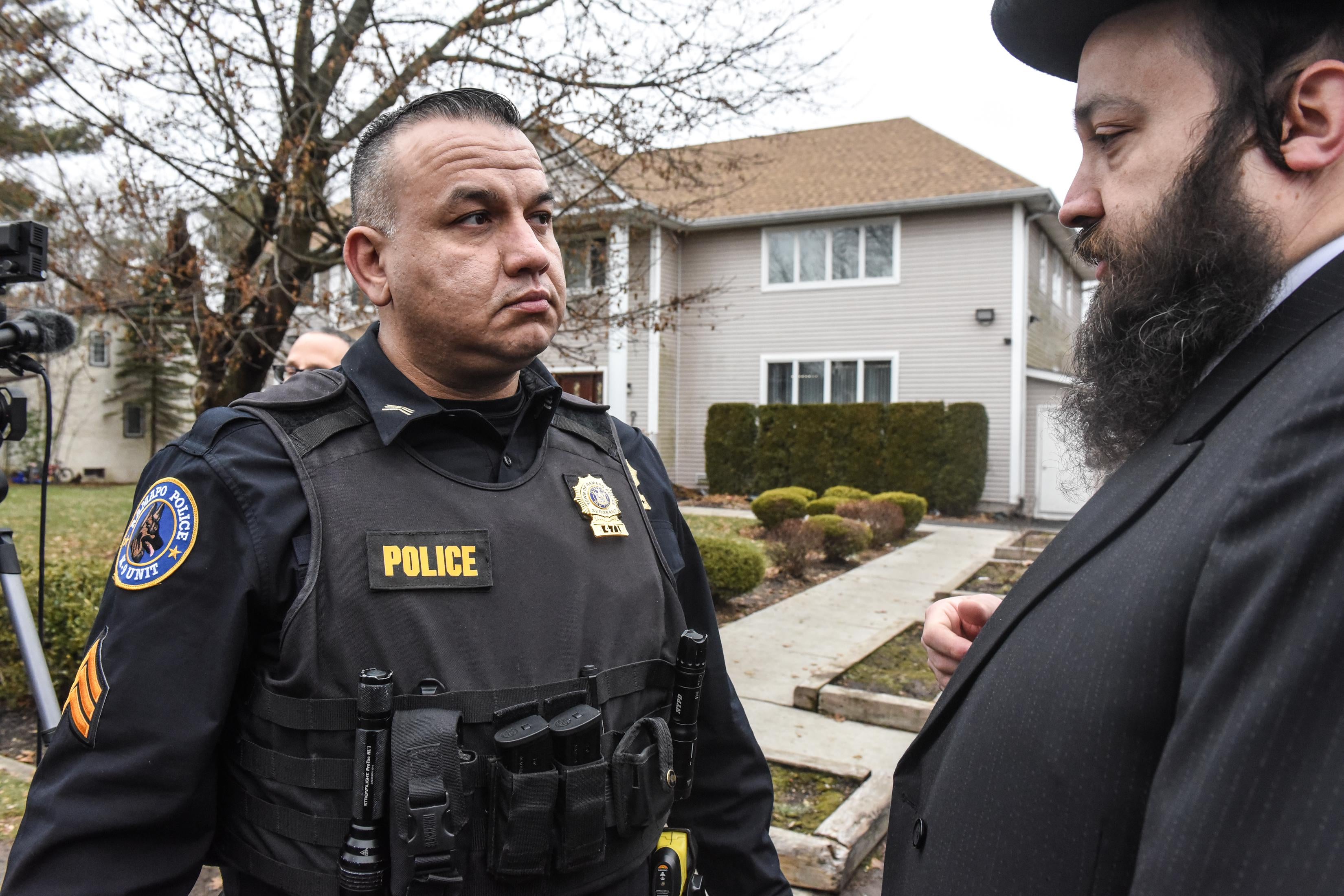 A police officer stands with another man in front of the house.