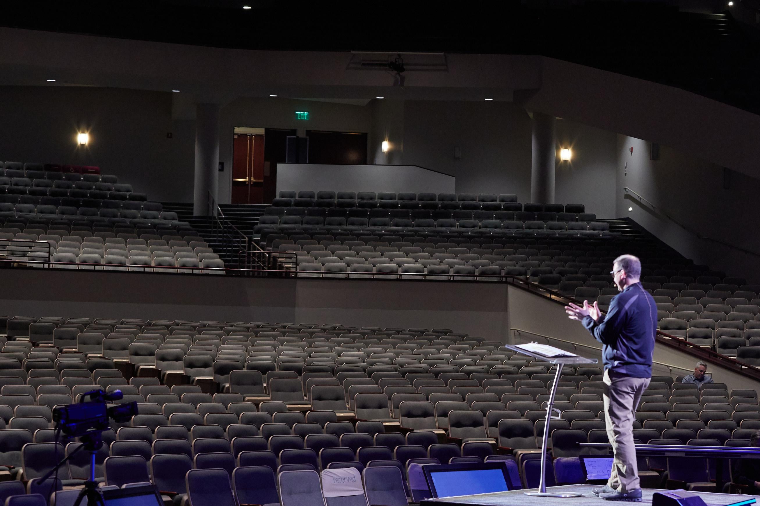 Troy Dobbs speaks at a podium before an empty auditorium.
