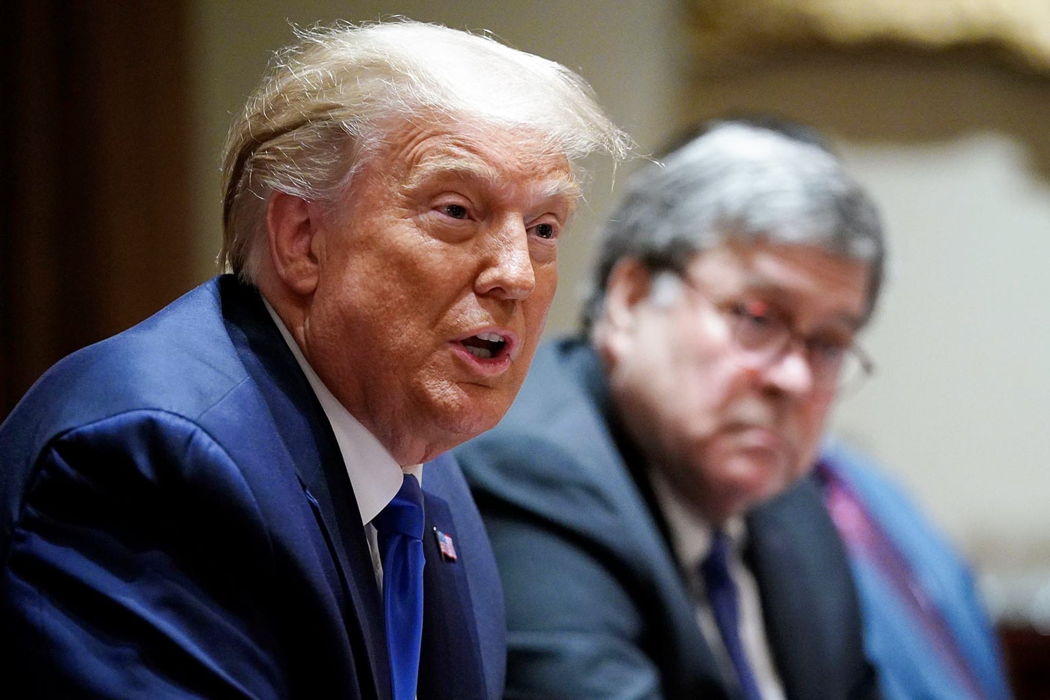 Trump and Barr sit at a table with their hands clasped.