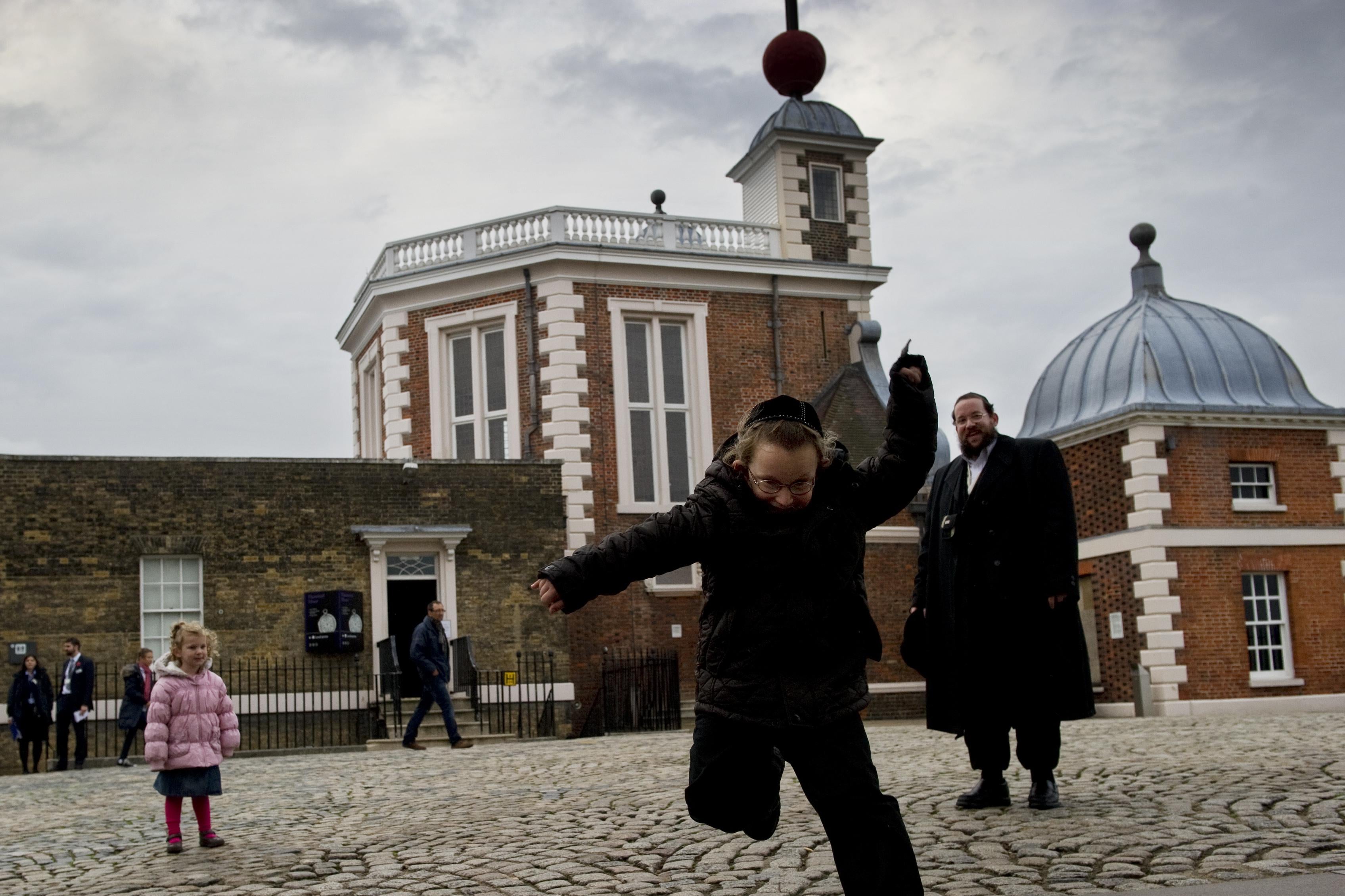 A tourist jumps over the Prime Meridian line at the Royal Observatory in Greenwich, London.