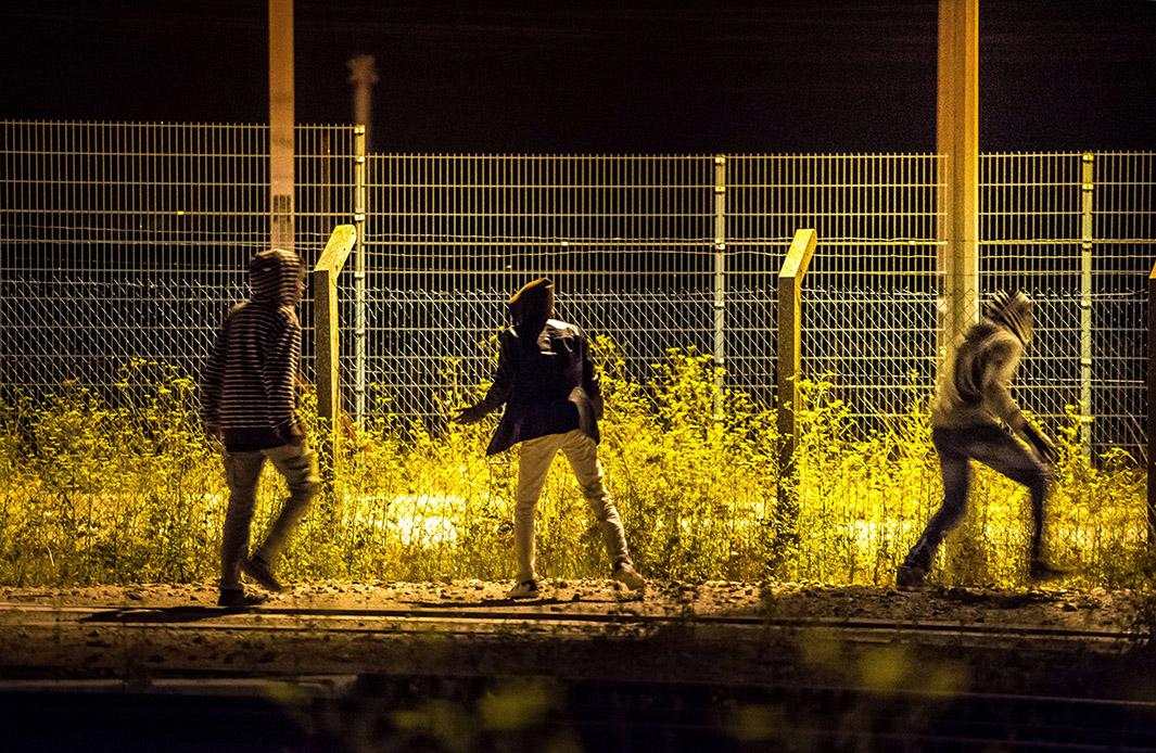 Refugees who passed a first fence look for another passage to access to the Eurotunnel terminal on Aug. 6, 2015, near Calais in northern France