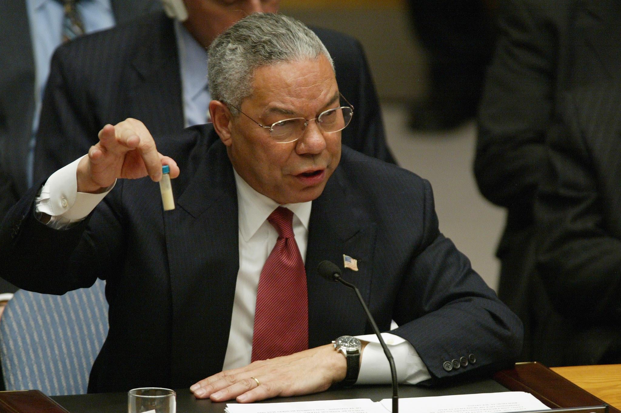 Colin Powell holds up a vial in front of a microphone, seated at the United Nations Security Council on Feb. 5, 2003.