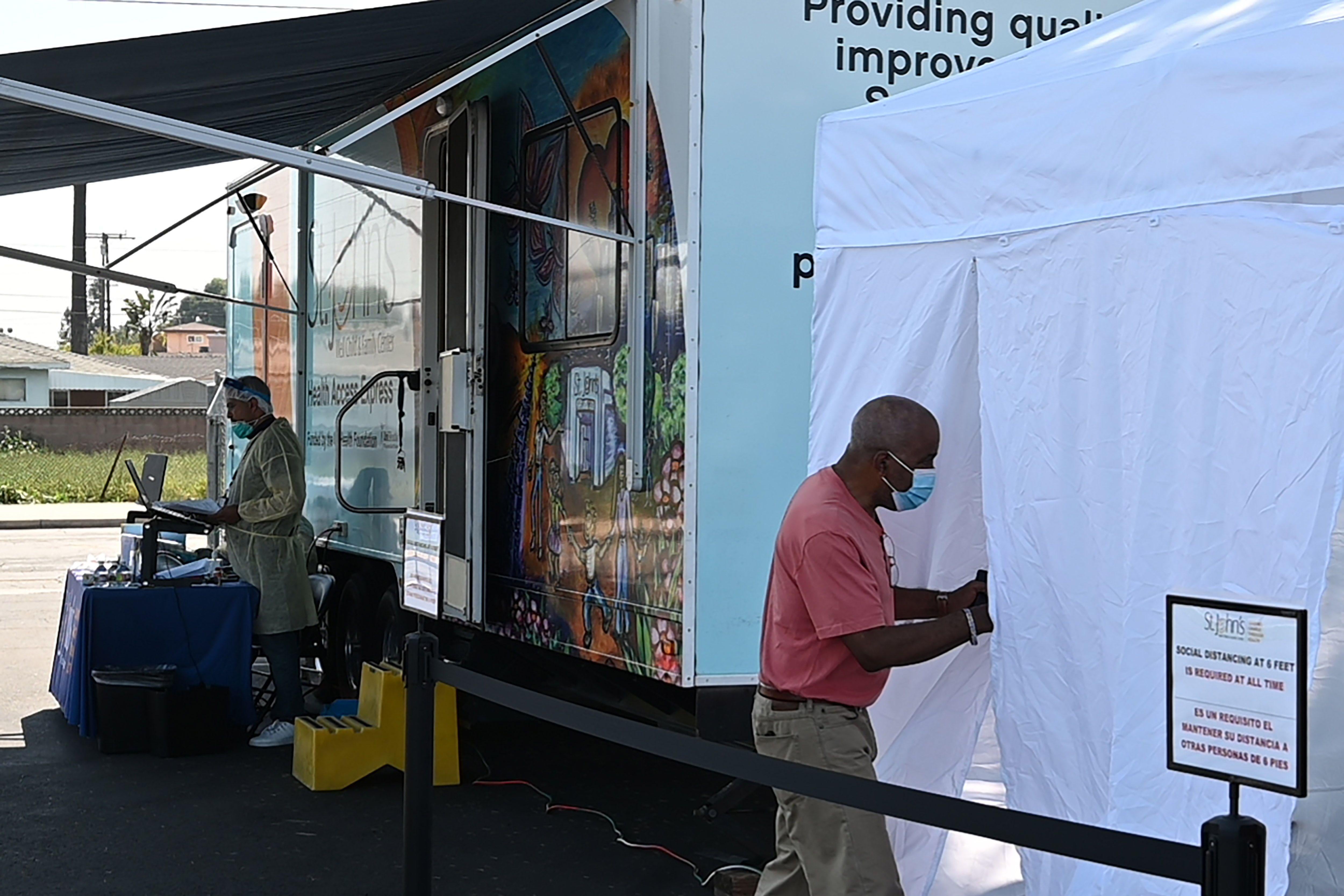A man walks into a tent to be tested for COVID-19 at a mobile testing station in a public school parking area in Compton.