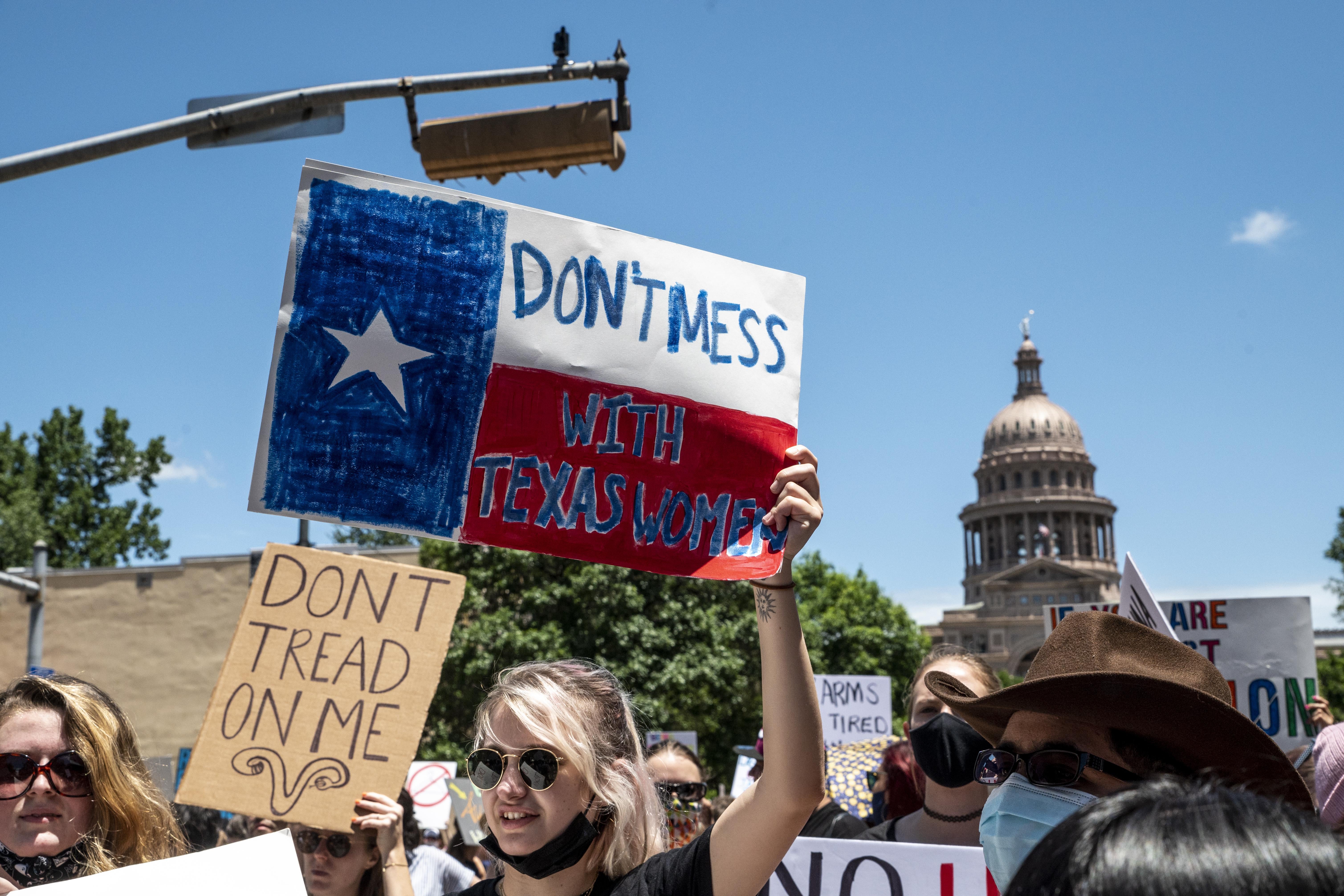 Protesters in front of the Texas Capitol with signs that read "Don't Mess With Texas Women."