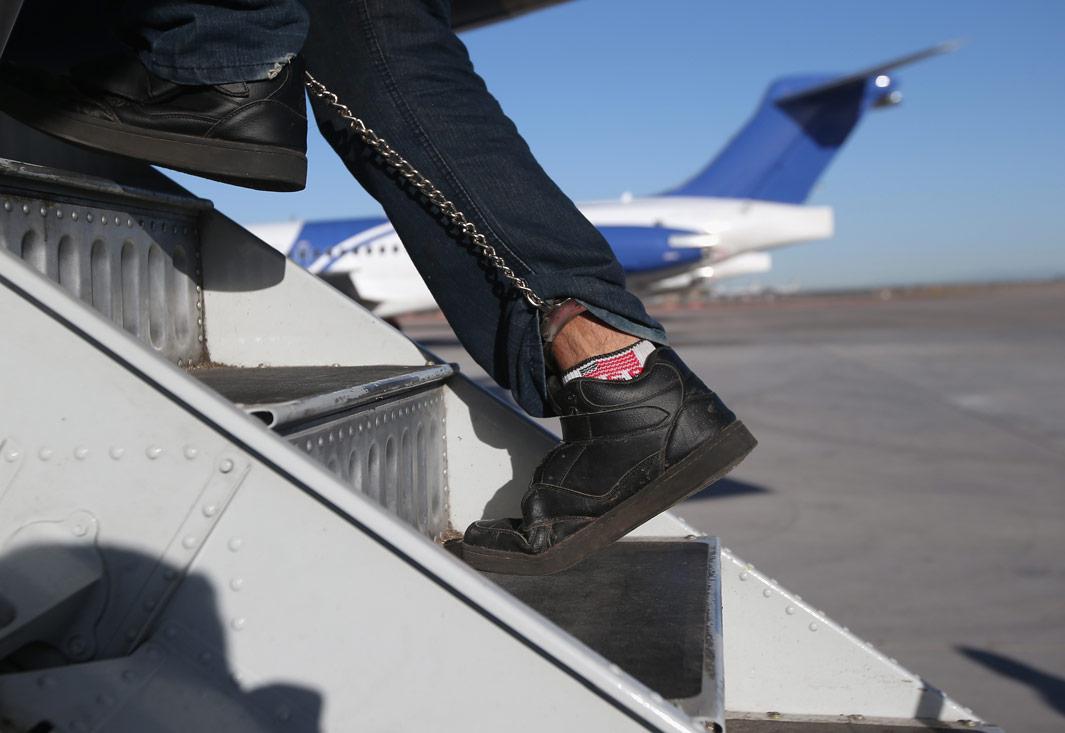 MESA, AZ - FEBRUARY 28: A Honduran immigration detainee, his feet shackled and shoes laceless as a security precaution, boards a deportation flight to San Pedro Sula, Honduras on February 28, 2013 in Mesa, Arizona. U.S. Immigration and Customs Enforcement (ICE), operates 4-5 flights per week from Mesa to Central America, deporting hundreds of undocumented immigrants detained in western states of the U.S. With the possibility of federal budget sequestration, ICE released 303 immigration detainees in the last week from detention centers throughout Arizona. More than 2,000 immigration detainees remain in ICE custody in the state. Most detainees typically remain in custody for several weeks before they are deported to their home country, while others remain for longer periods while their immigration cases work through the courts.