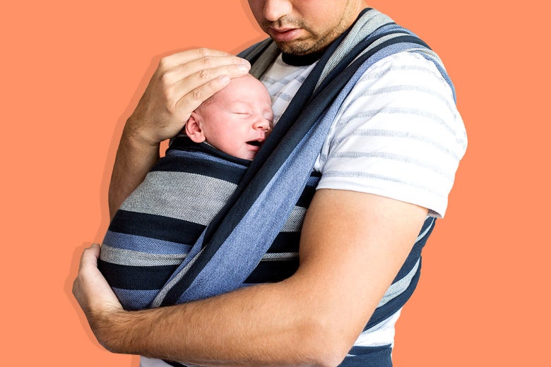 A man holding a sleeping infant in a cross-chest carrier.