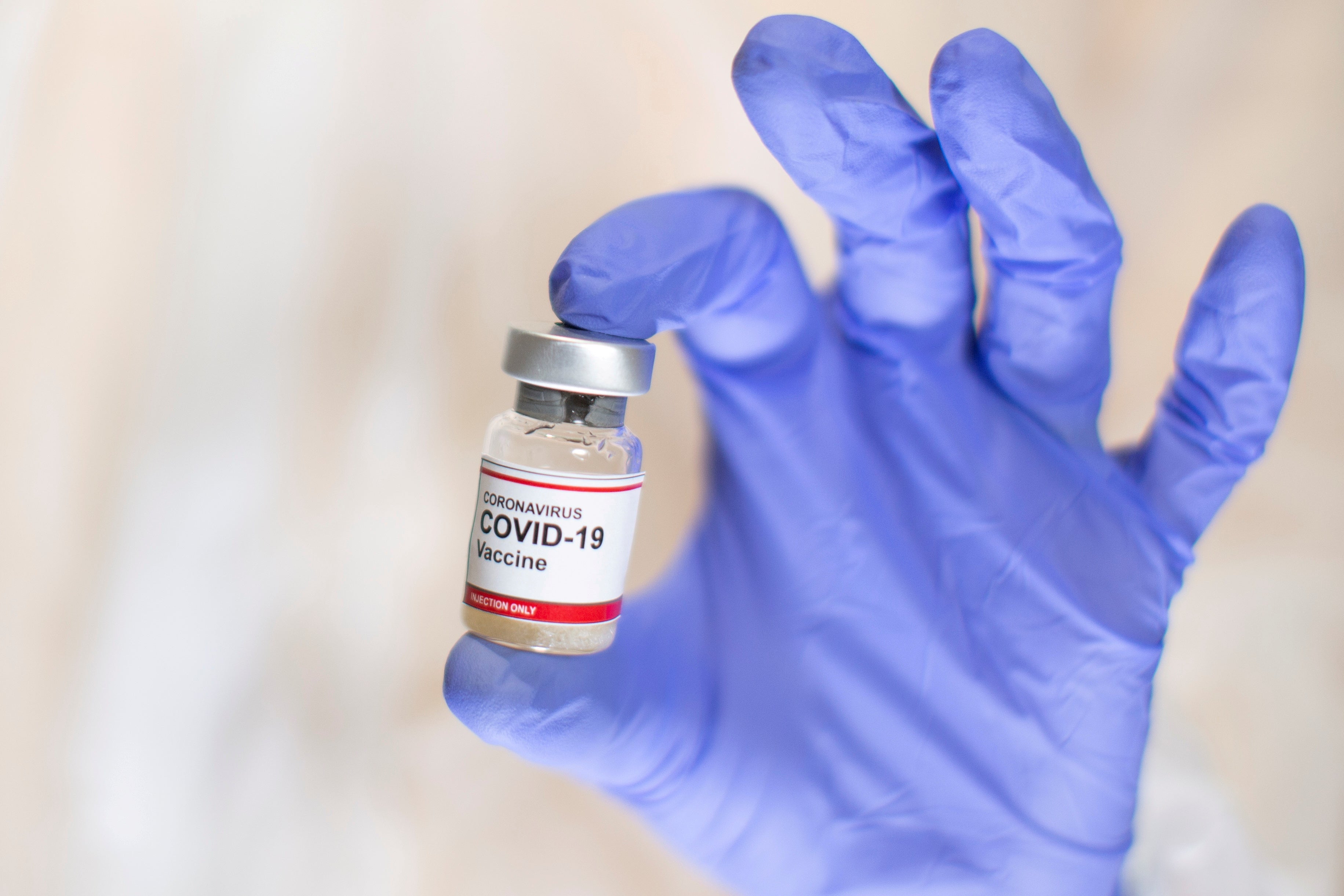 A woman holds a small bottle labeled with a "Coronavirus COVID-19 Vaccine" sticker