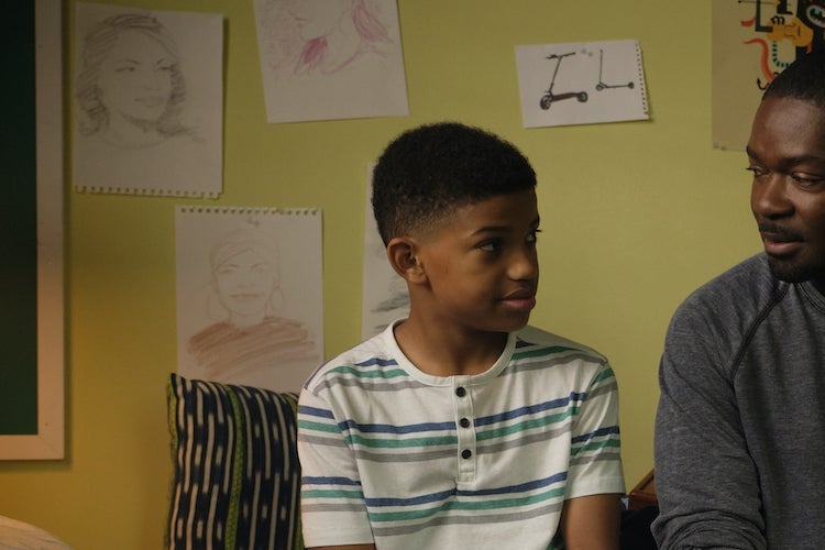 Lonnie Chavis and David Oyelowo smile at each other in front of a wall covered in drawings.