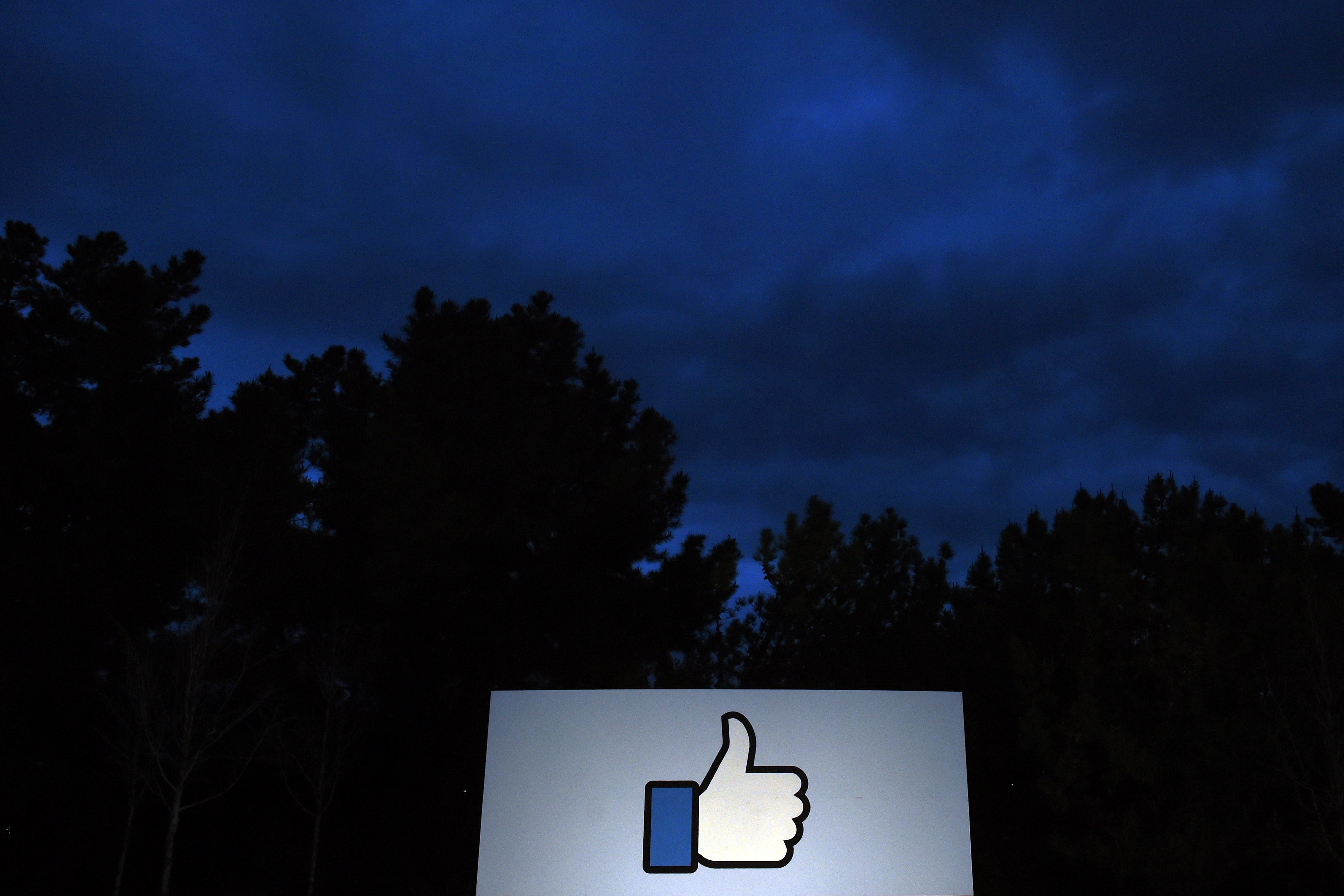 A thumbs-up "like sign" in front of trees at the entrance to Facebook headquarters in Menlo Park, California.