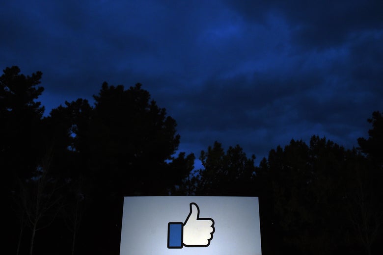 A thumbs-up "like sign" in front of trees at the entrance to Facebook headquarters in Menlo Park, California.