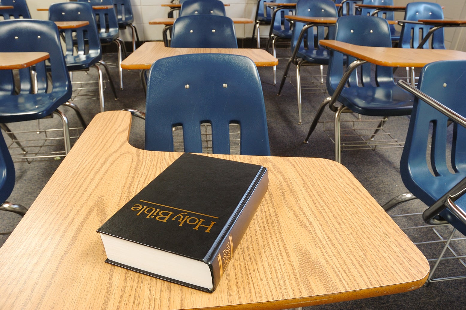 A child's classroom desk, with a Bible on it.