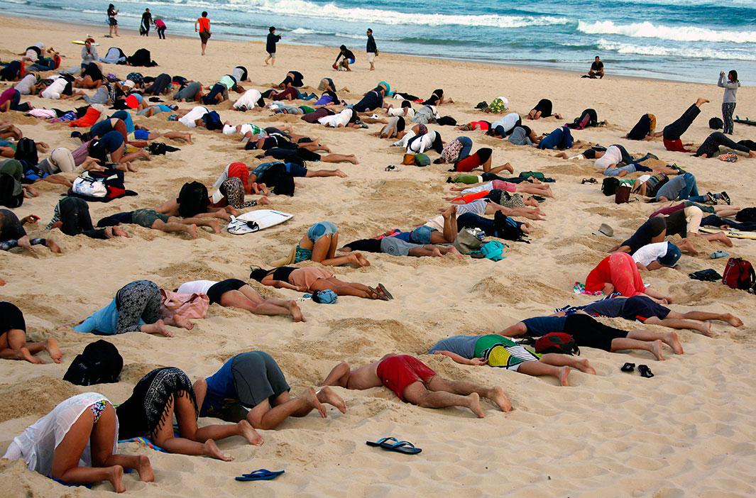 About 400 demonstrators participate in a protest by burying their heads in the sand at Sydney’s Bondi Beach on Nov. 13, 2014. The protest, held ahead of Saturday’s G20 summit in Brisbane, was being promoted as a message to Australian Prime Minister Tony Abbott’s government that, “You have your head in the sand on climate change.” 