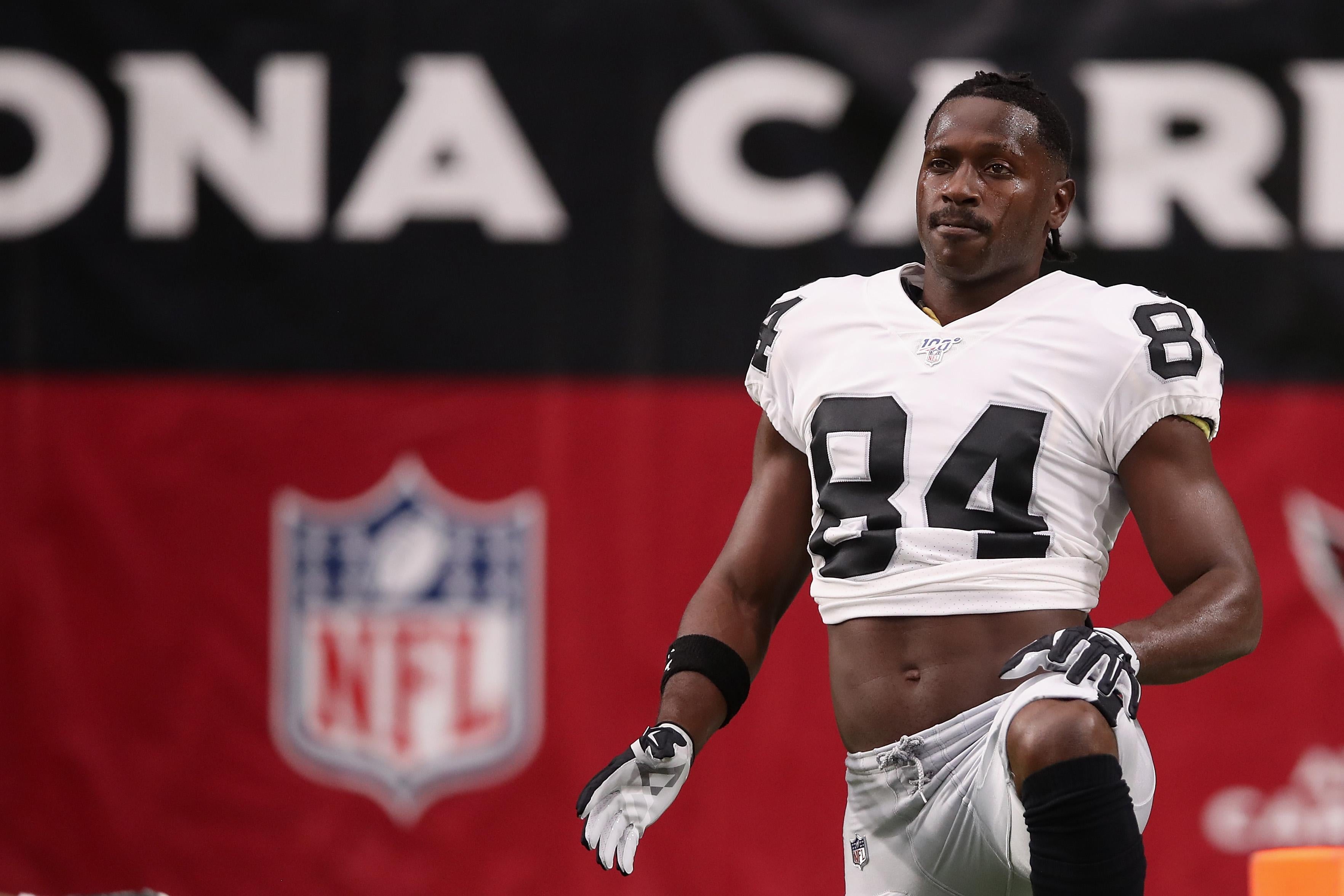 Antonio Brown stretches on field in a Raiders jersey.