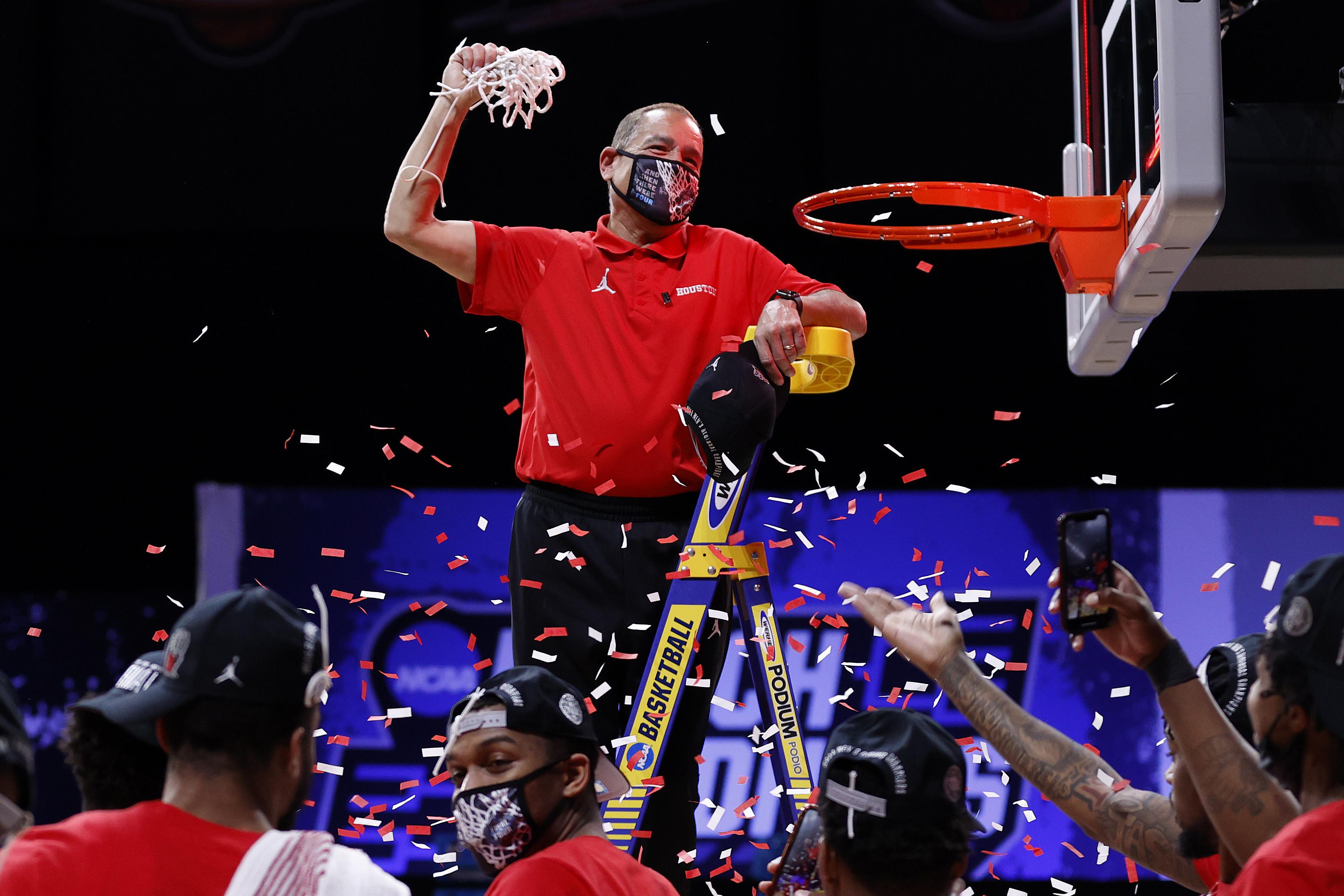 Houston coach Kelvin Sampson stands on a ladder and holds a net as confetti flies around him.