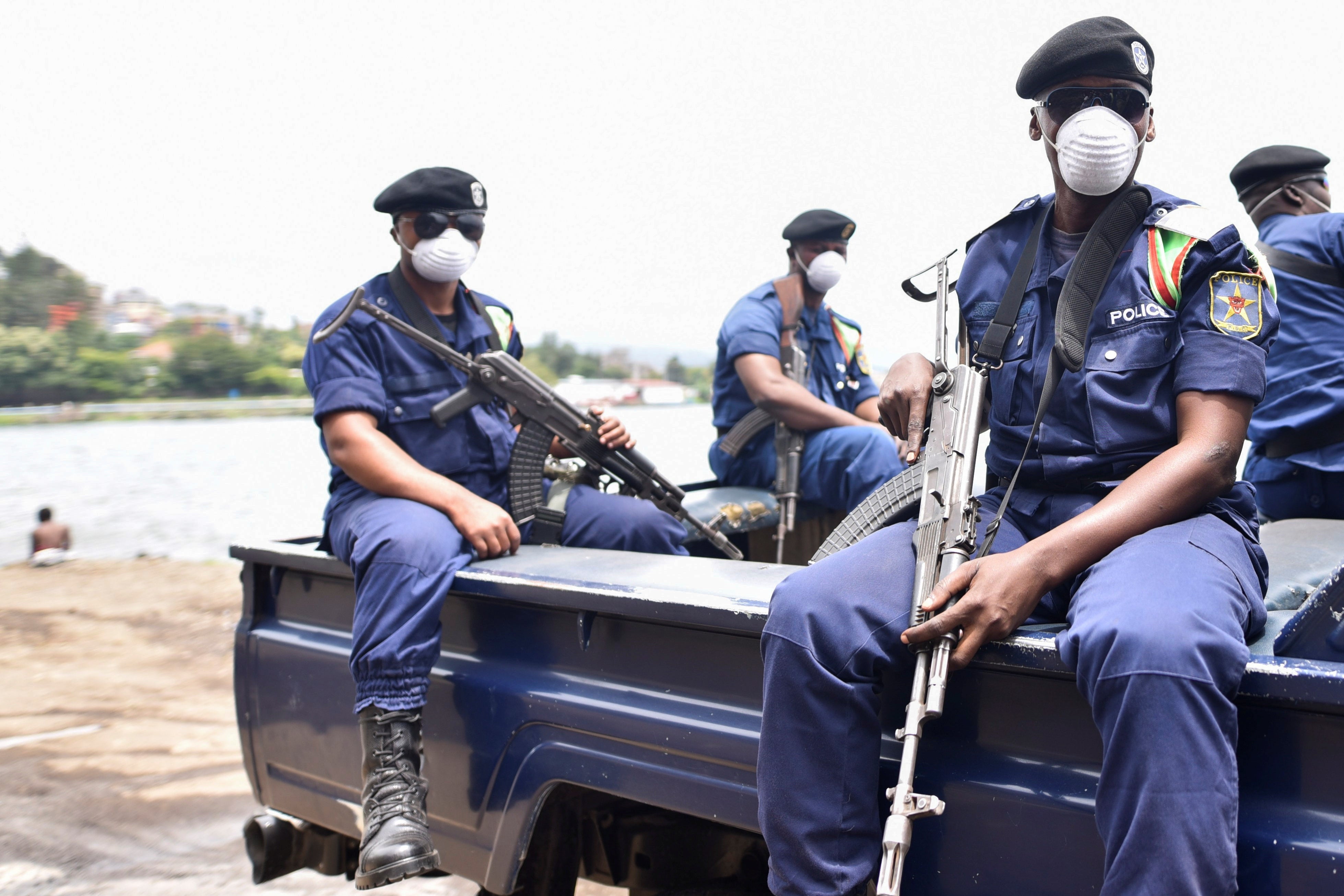 Police wearing masks and holding guns sit in the back of a pickup