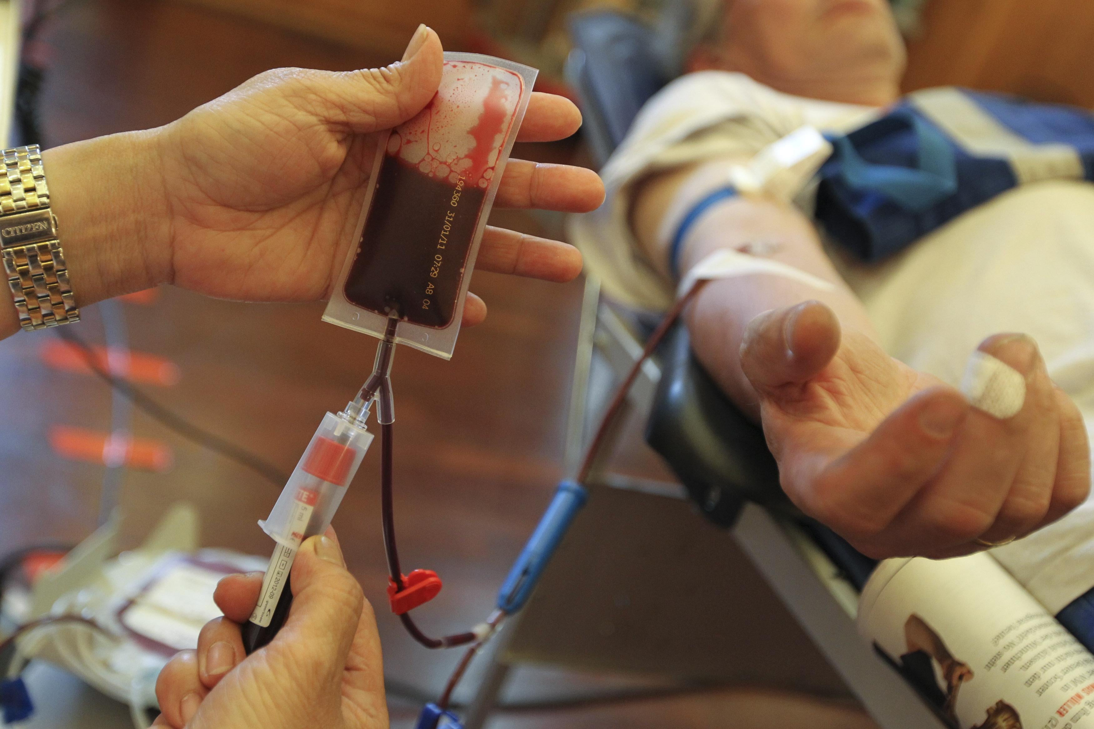 A nurse assists a man donating blood 
