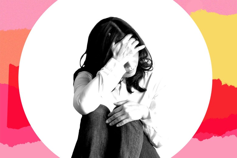 A woman sits on the ground and holds her forehead in her hand.