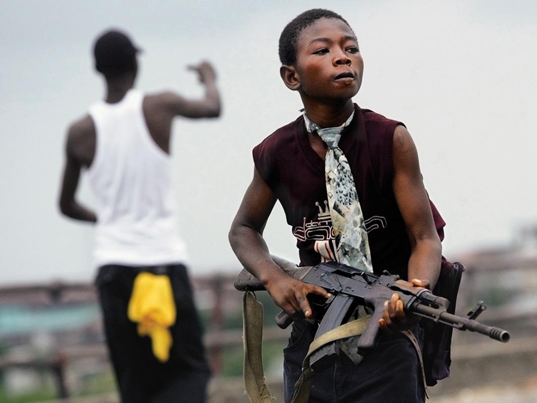 A child Liberian militia soldier loyal to the government walks away from firing on July 30, 2003, in Monrovia, Liberia. Sporadic clashes continue between government forces and rebel fighters in the fight for control of Monrovia.