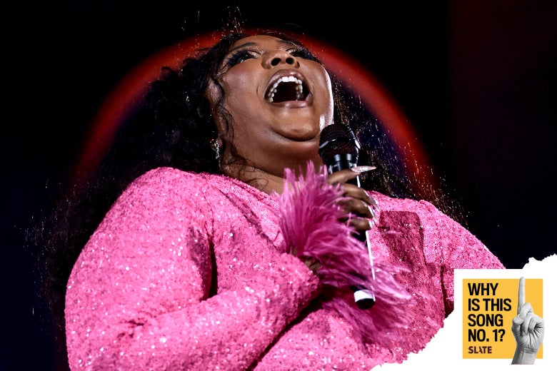 The pop star Lizzo stands on a stage singing into a microphone.