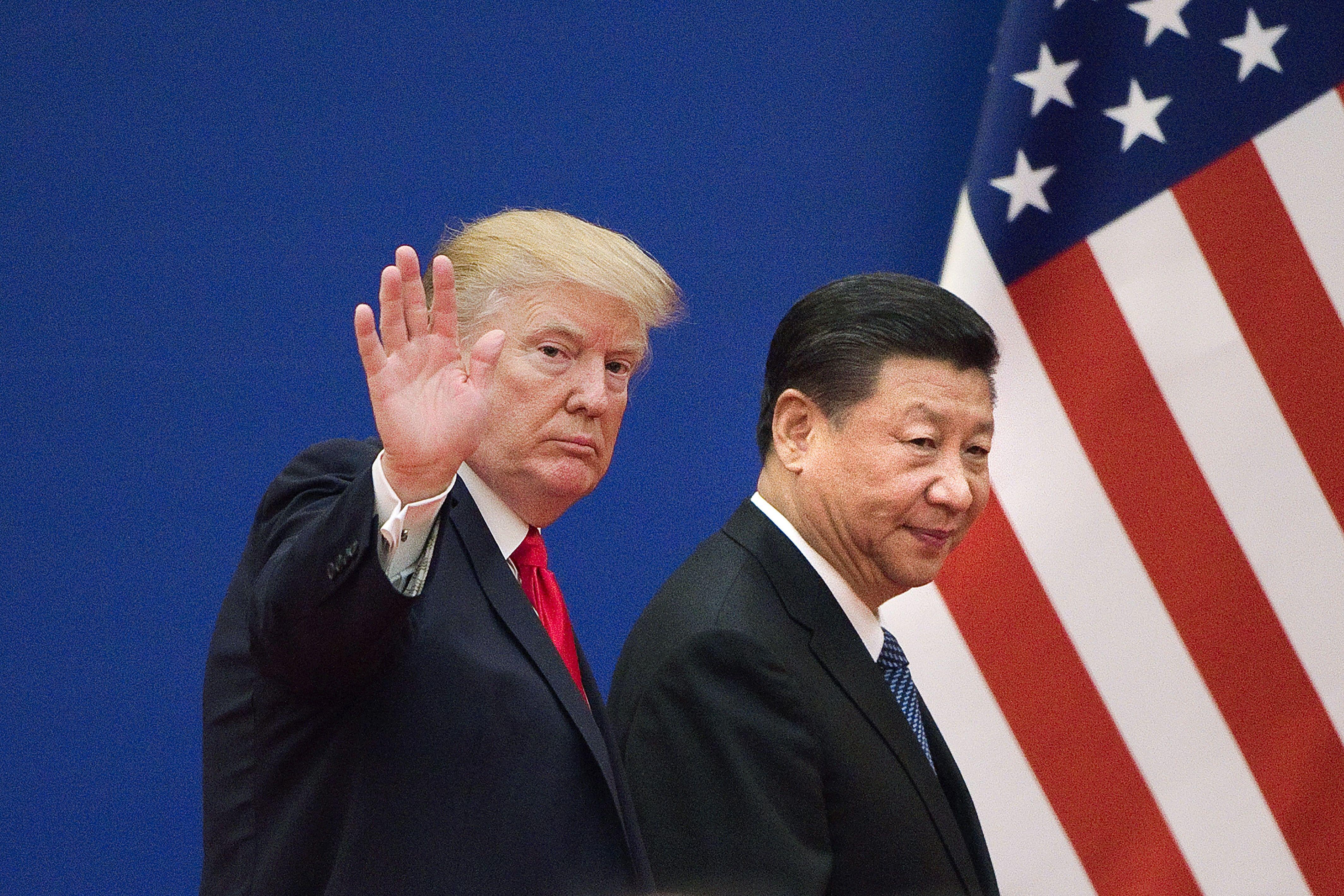 Trump waves as he and Xi walk past an American flag.