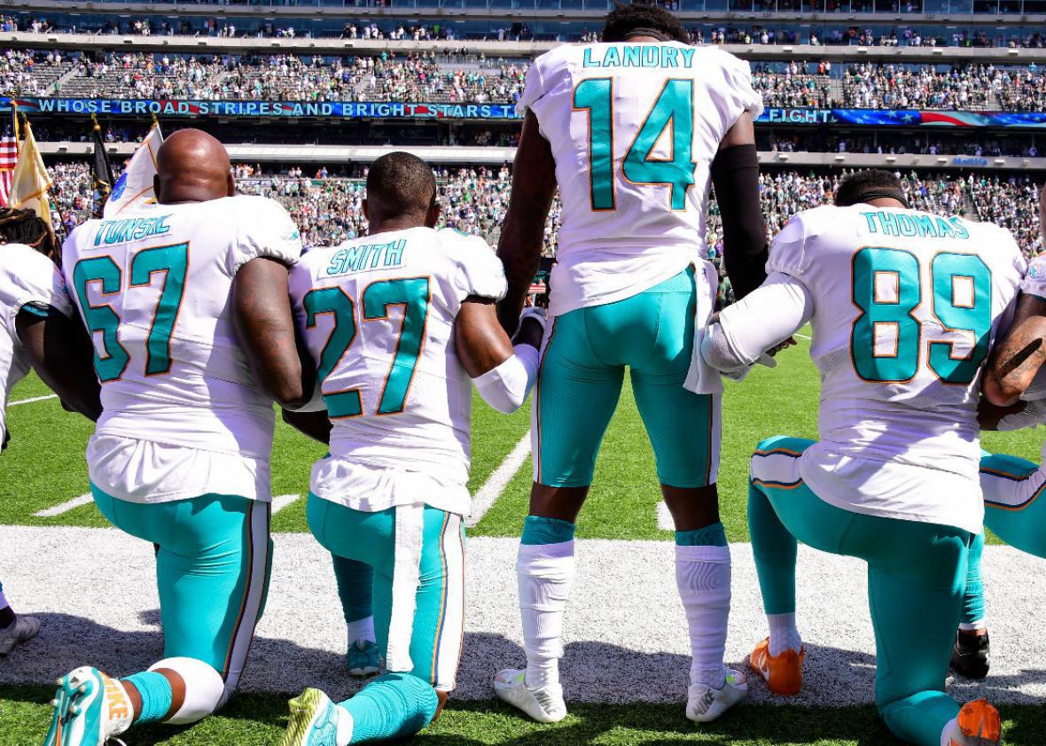 Members of the Miami Dolphins kneel during the national anthem 