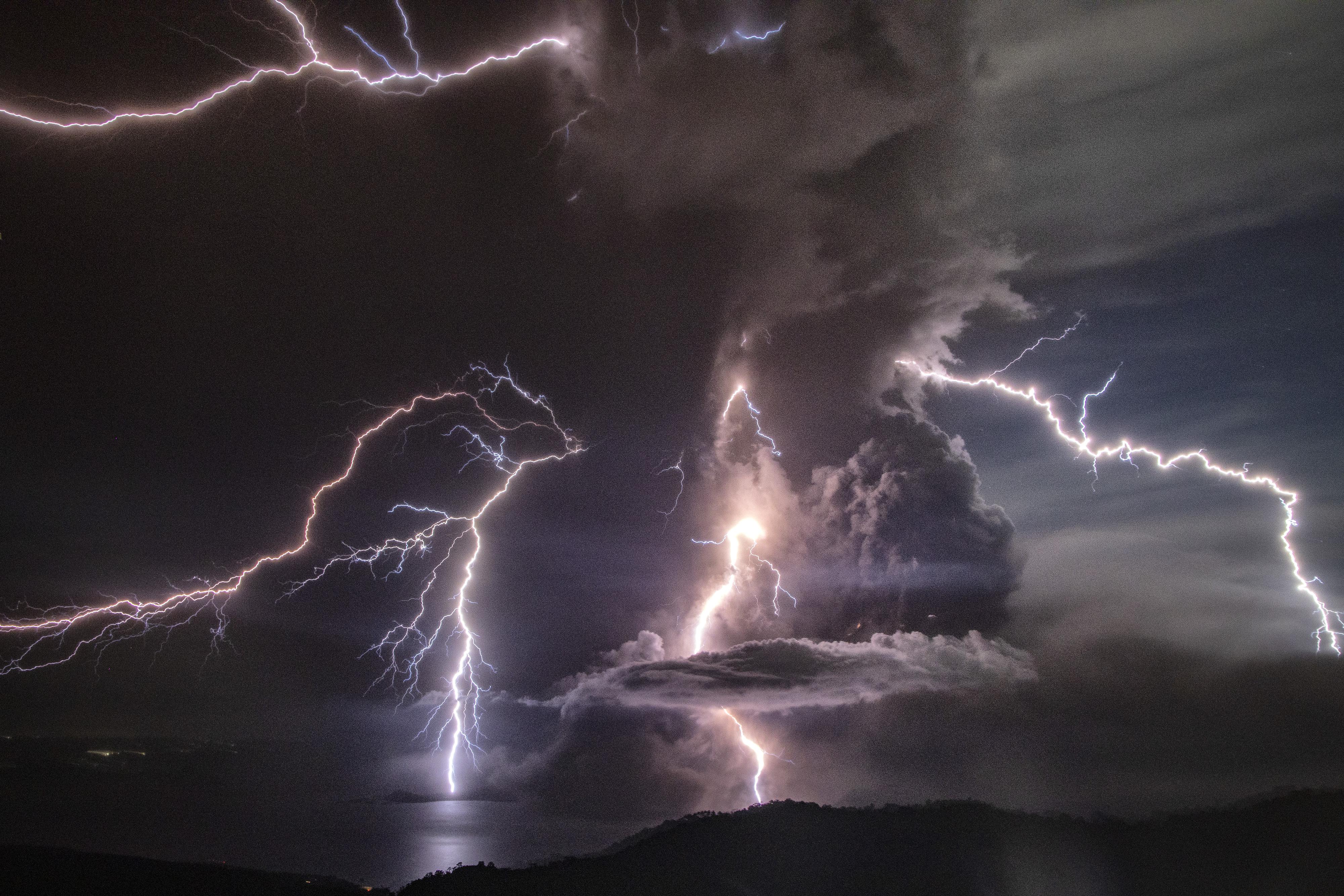 Lightning strikes amid the column of ash from the volcano.