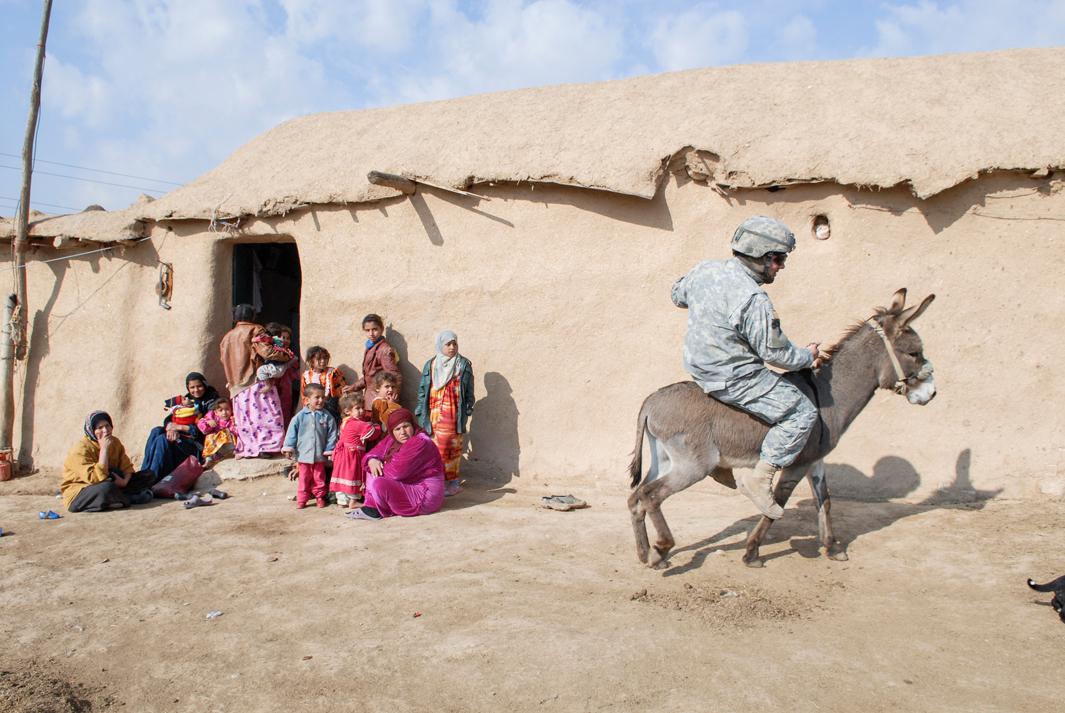 The wary inhabitants of this isolated village in Nineveh had never seen an American patrol, and asked what country they were from. They had heard of America, and served sugary tea to the soldiers but otherwise kept their distance. The troops took turns riding the donkey and posed for pictures holding lambs. In the Bible, Nineveh is described as a wicked city. God sent the prophet Jonah to preach there, and its inhabitants repented. God decided to spare the city.NINEVEH. IRAQ. 2006