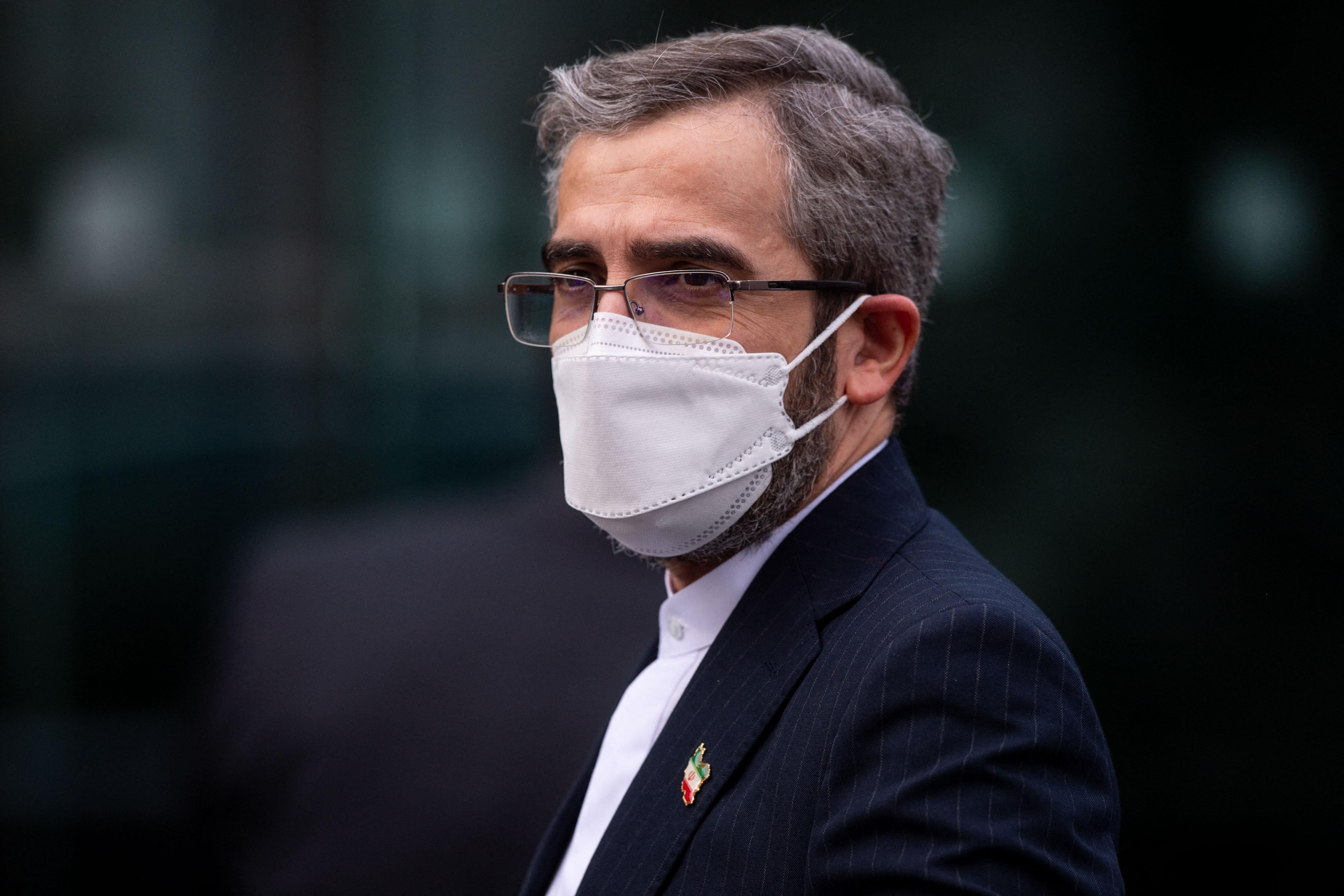A close-up of Ali Bagheri Kani wearing a white mask and a suit