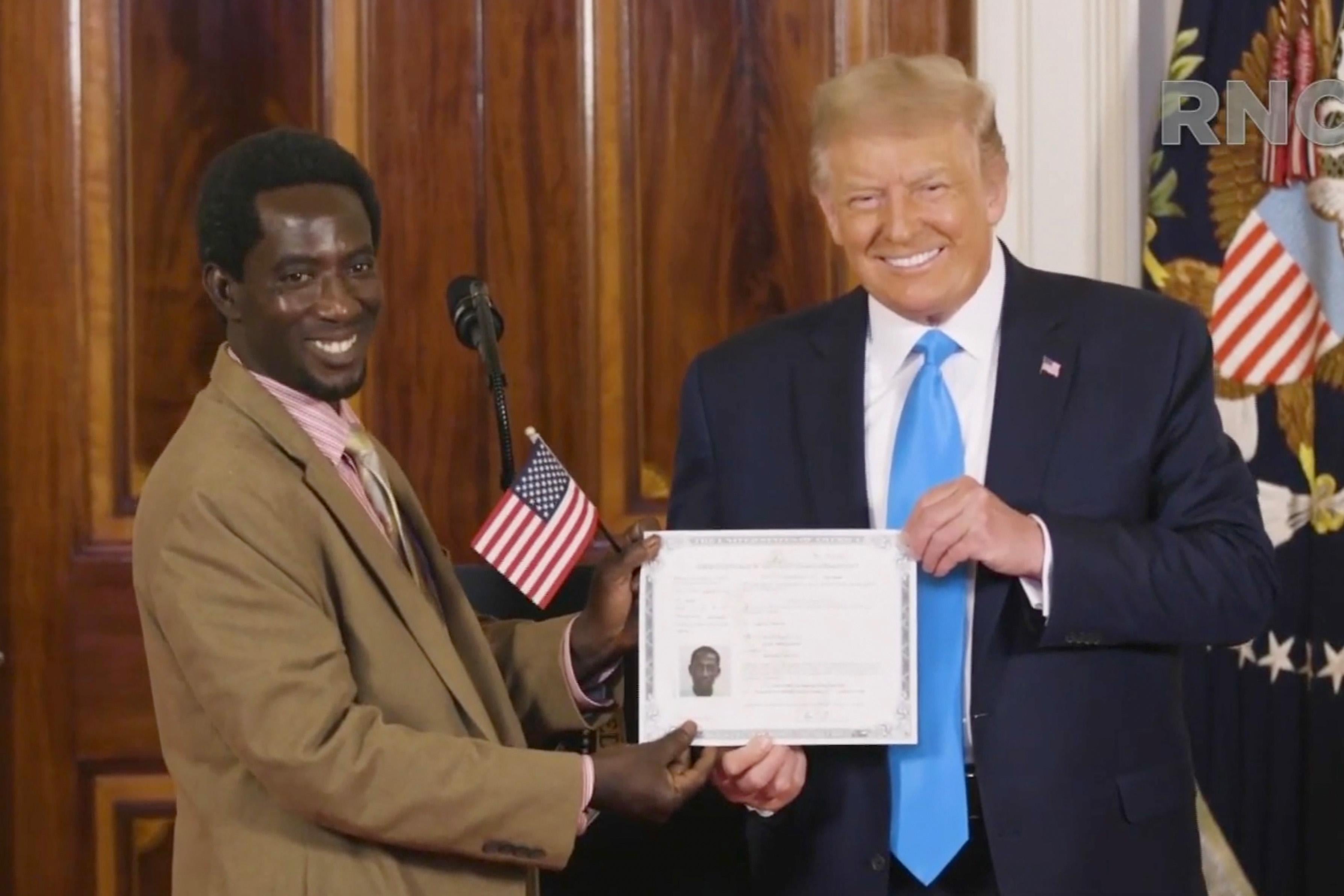 Donald Trump holds a certificate with an American flag alongside a newly inaugurated citizen.