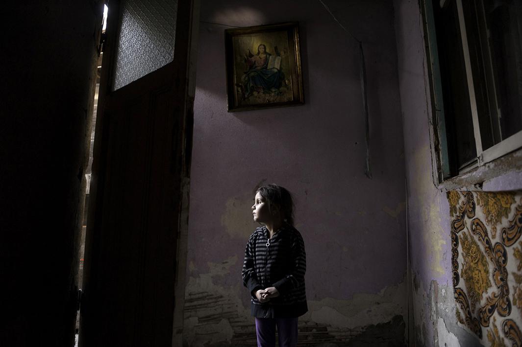 Four-year-old Ana-Maria Tudor, above, stands in the light of her doorway in Bucharest, Romania, hoping for a miracle as her family faces eviction from the only home they have ever had. Her father recently had a gall bladder surgery that resulted in an infection and left him unable to work. The one room they live in has no bathroom or running water. 