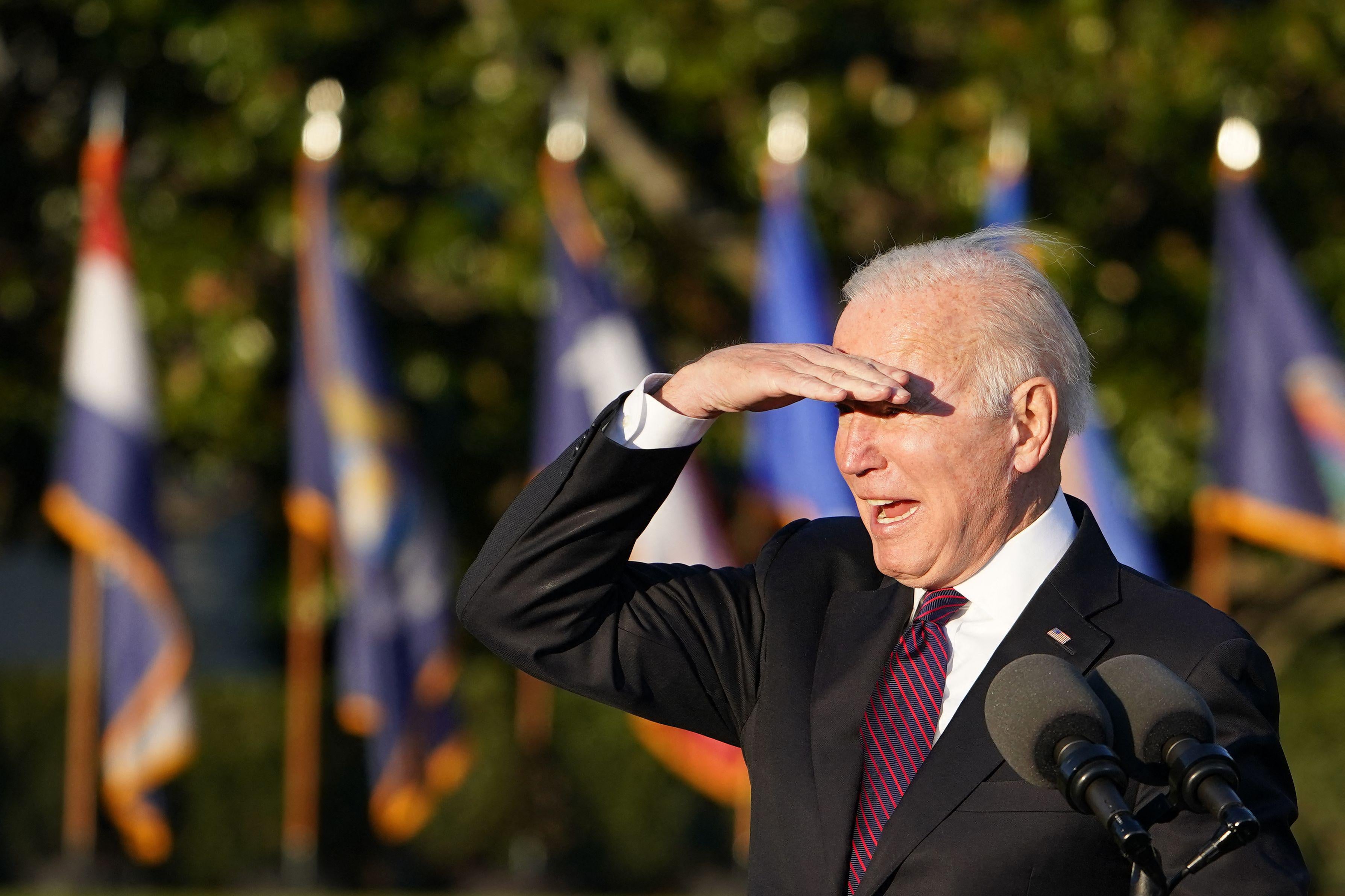 Joe Biden looks out at a crowd, shielding his eyes from the sun.