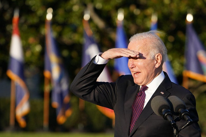 Joe Biden looks out at a crowd, shielding his eyes from the sun.