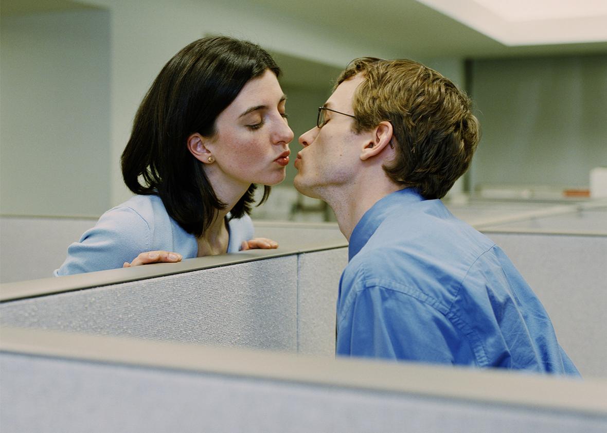 Man and woman in seperate cubicles, kissing