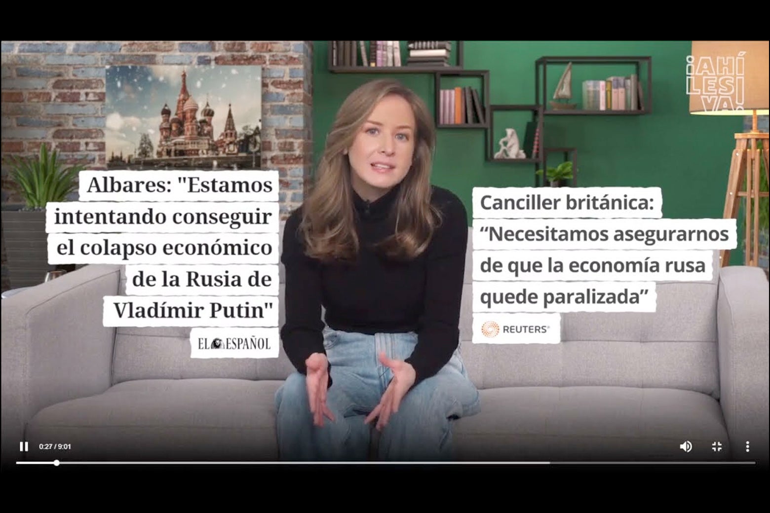A screenshot of a YouTube show from the Russian-backed program Ahi les Va. Host Inna Afinogenova is seated on a couch in a well decorated living room, and superimposed on the screen next to her are mainstream media headlines, in Spanish, about Russia's economy.
