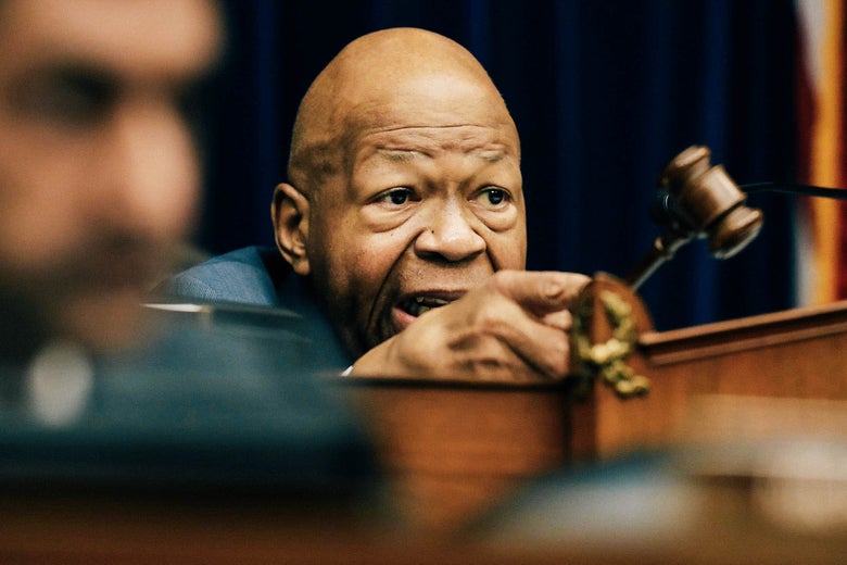 Elijah Cummings holds a gavel while seated at the dais.
