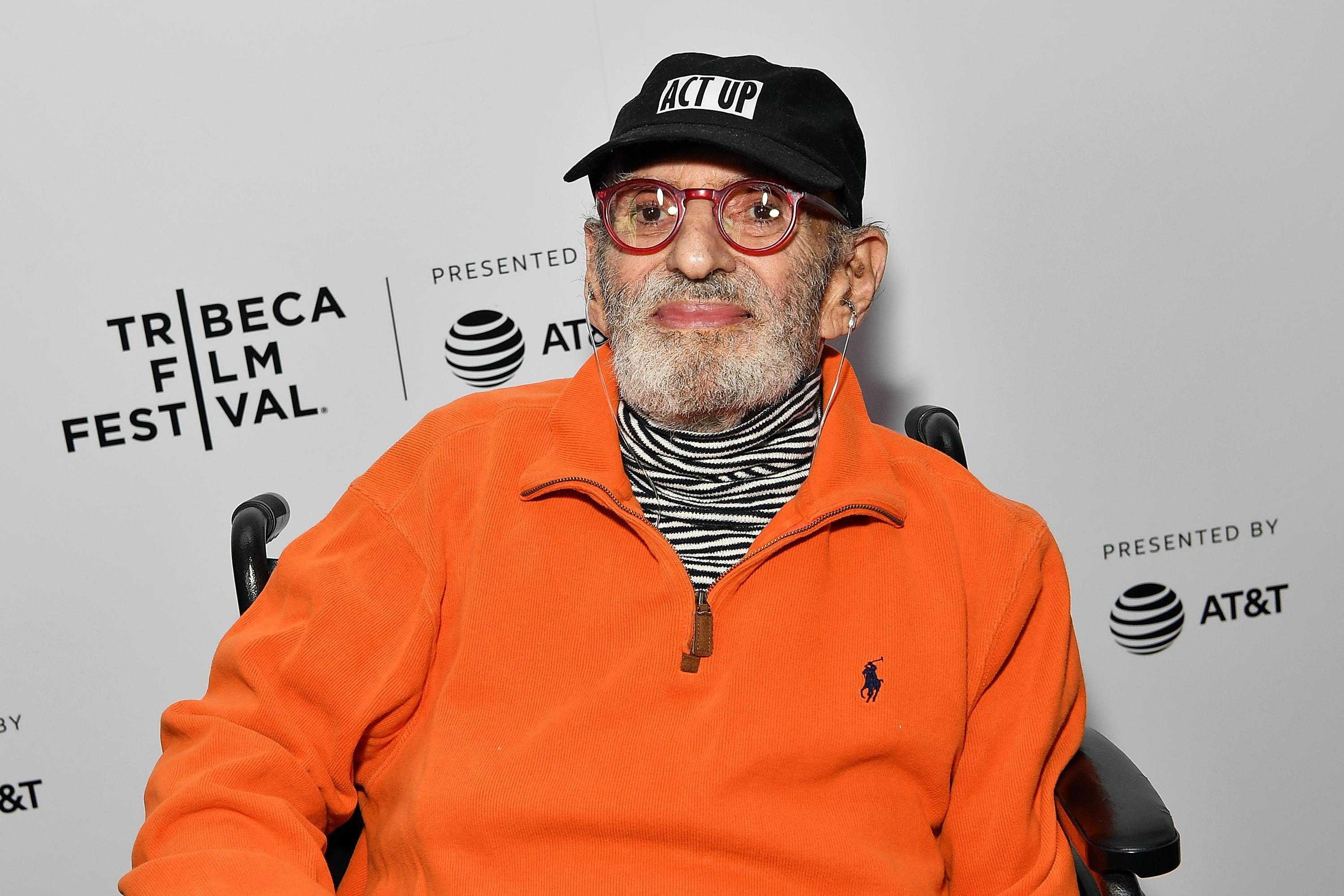 Larry Kramer seated in front of a Tribeca festival backdrop.