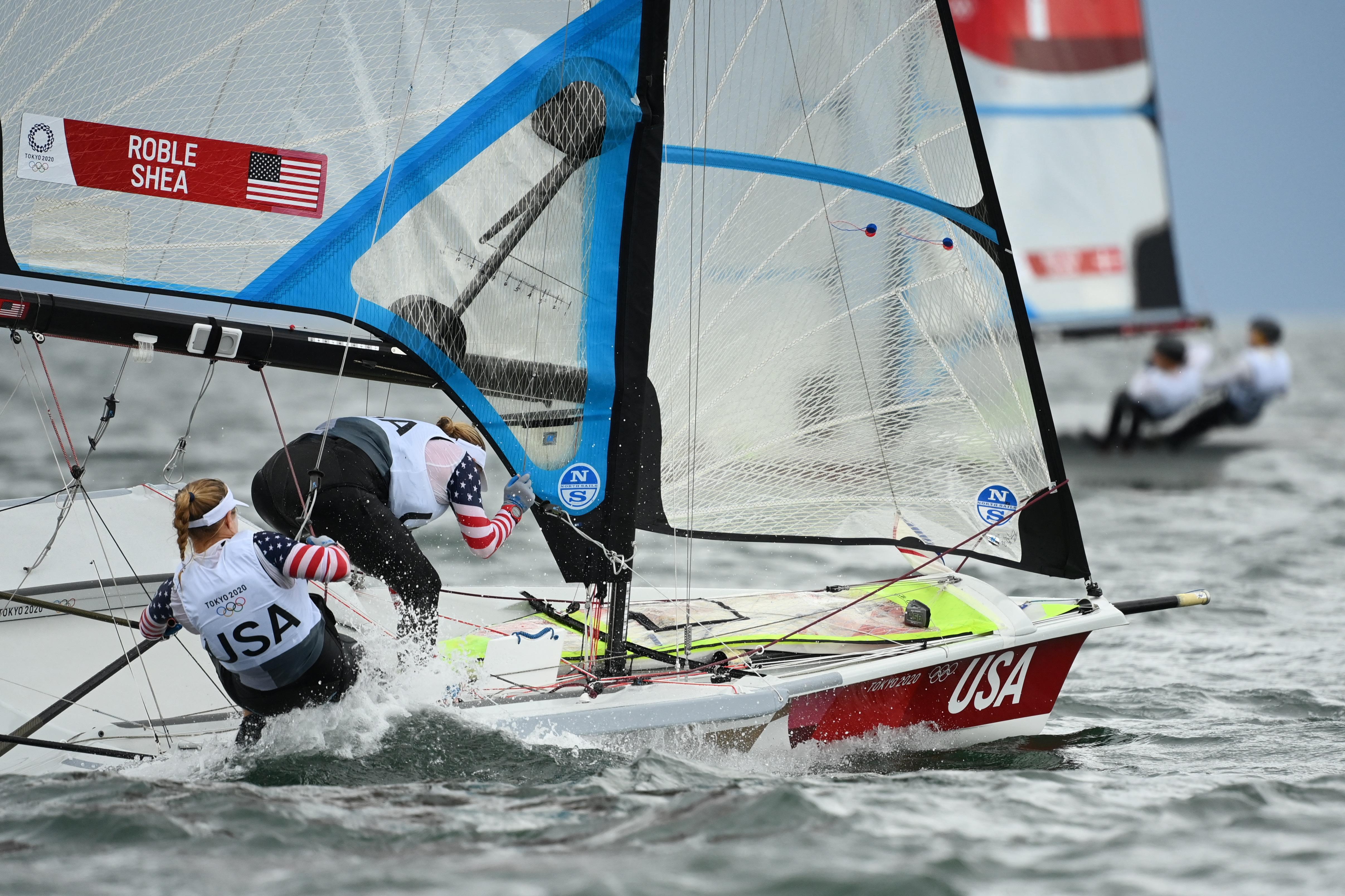 Two women falling into the water from the back of their boat