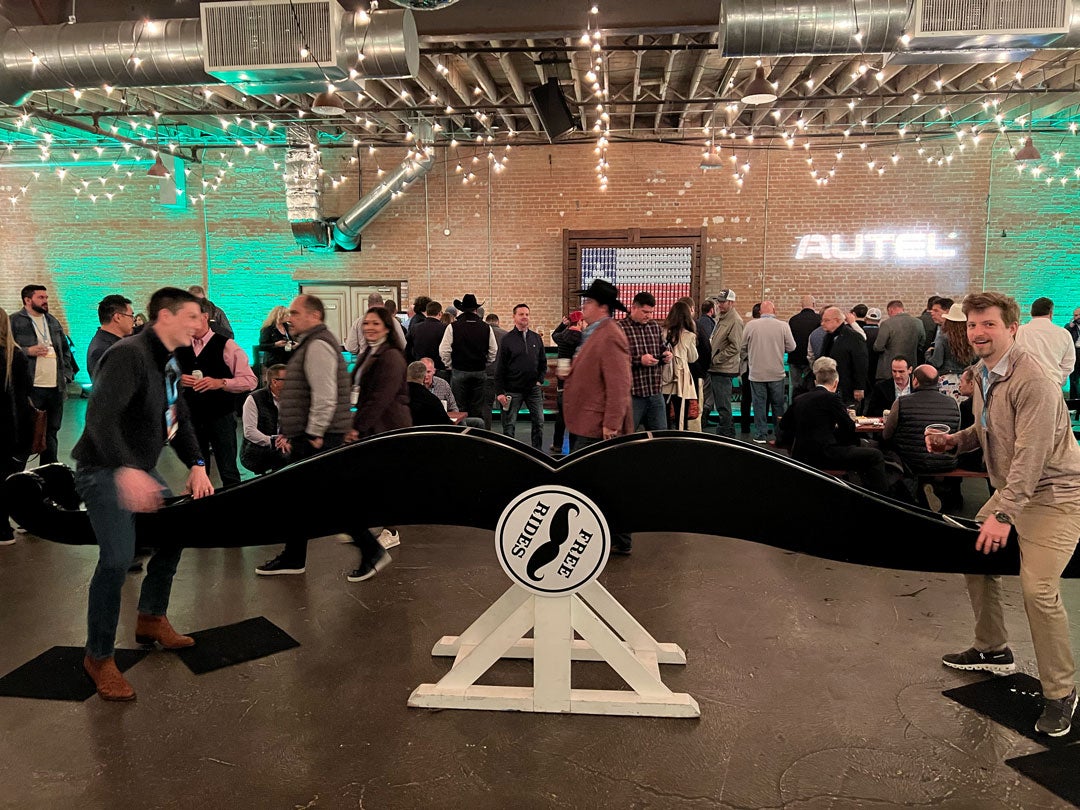 In a large brick-walled room, two men get ready to take a seat on either side of the seesaw, labeled "Free Rides." 