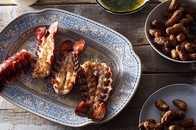 Cooked, halved lobster tails on a decorative platter.