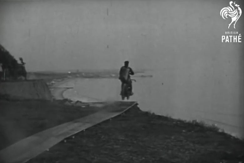 In a still frame from a 1926 newsreel, a man on a motorcycle flies off a cliff.
