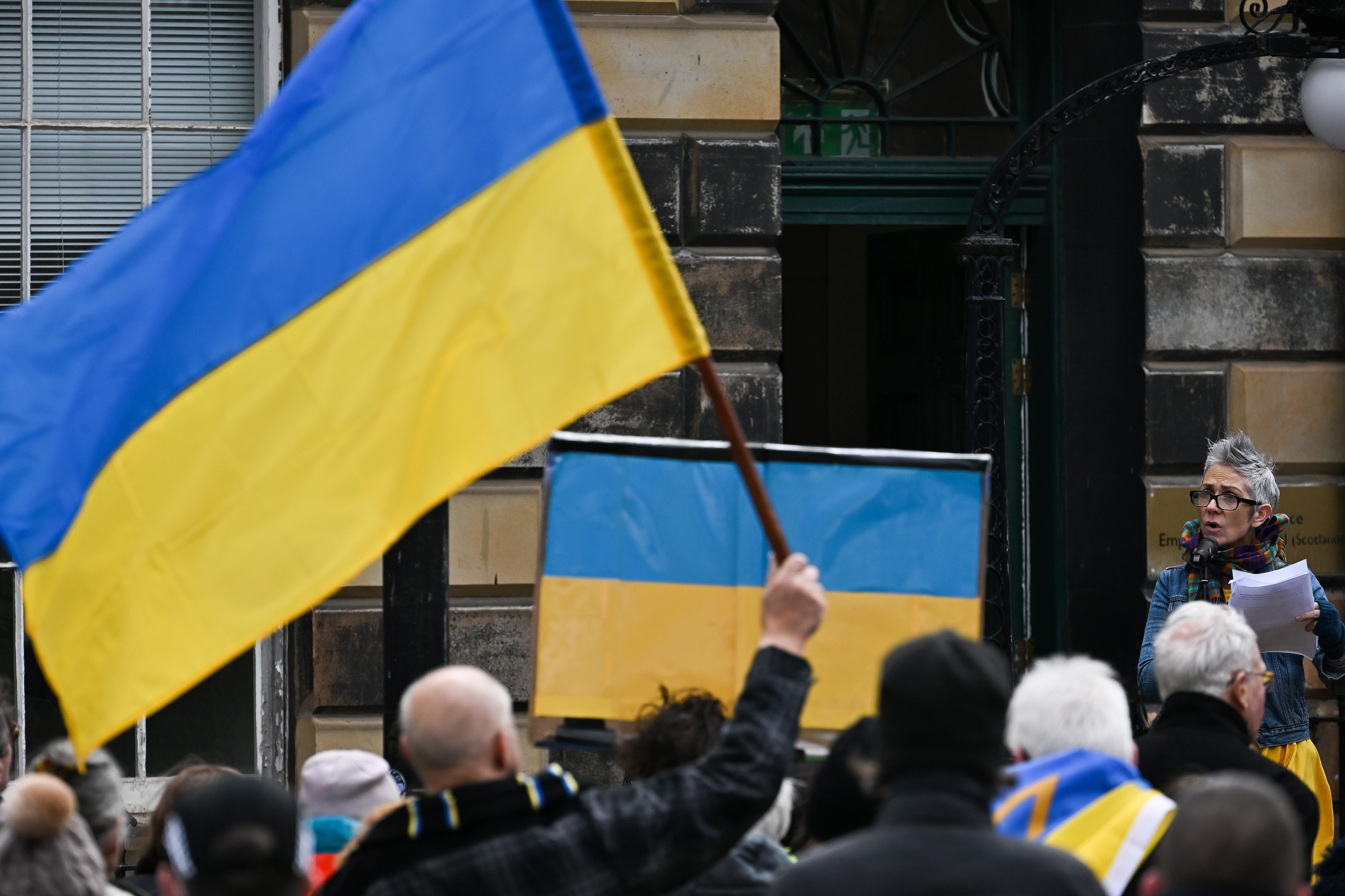 Protesters hold up Ukrainian flags as a woman speaks at the rally