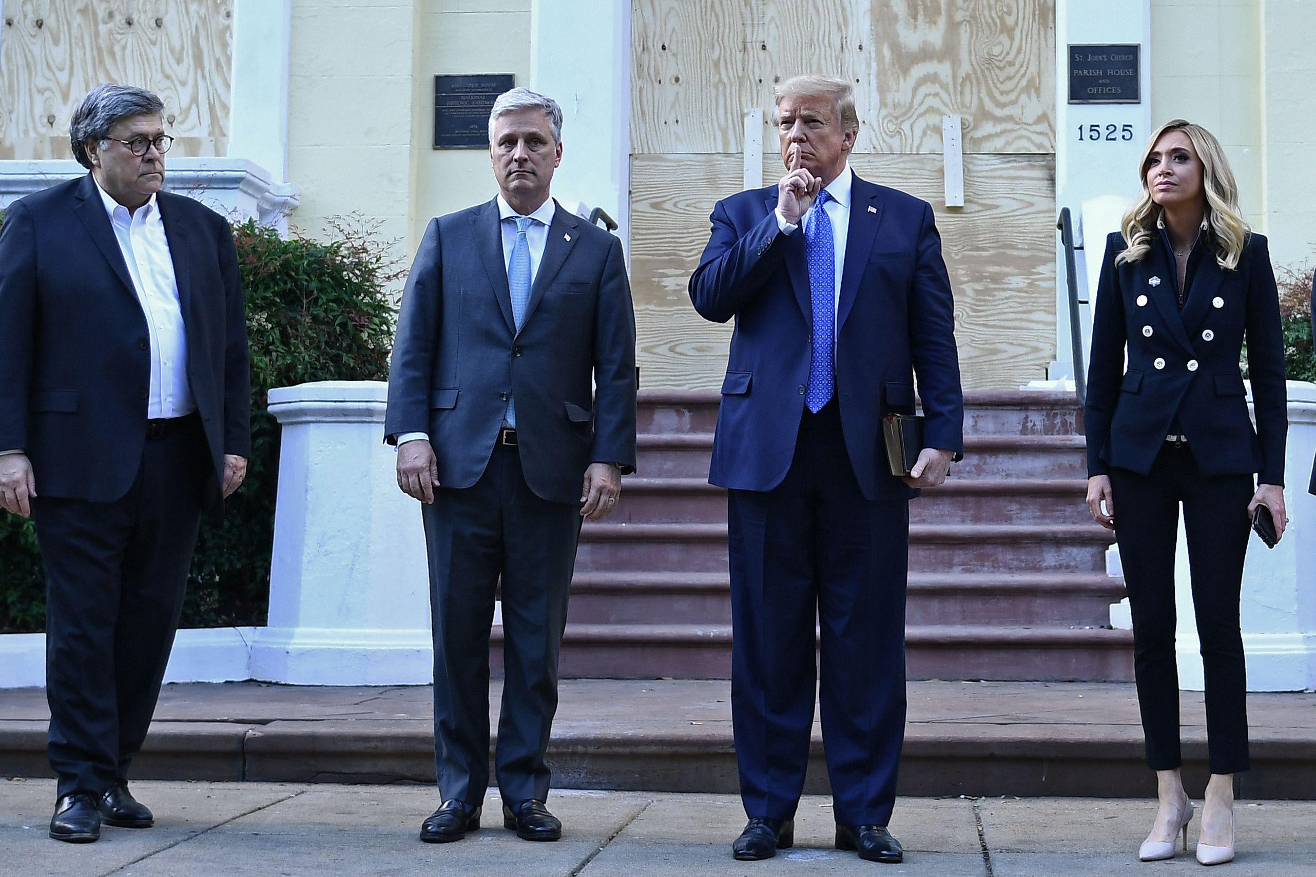 President Donald Trump holds up a Bible as he gestures alongside William Barr, Robert O'Brien, and Kayleigh McEnany outside of St John's Episcopal Church.