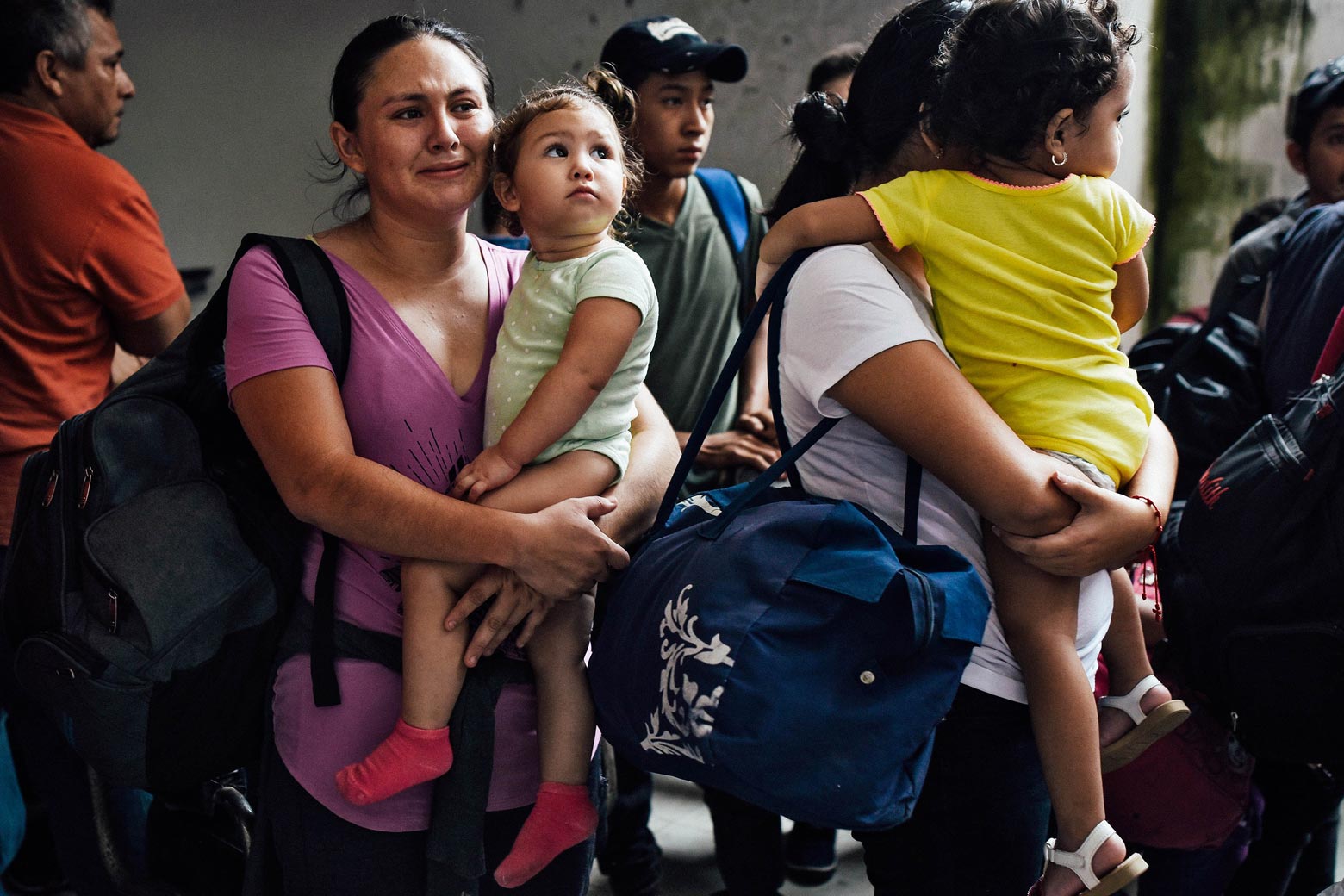 A group of migrants, including two mothers holding children in their arms.