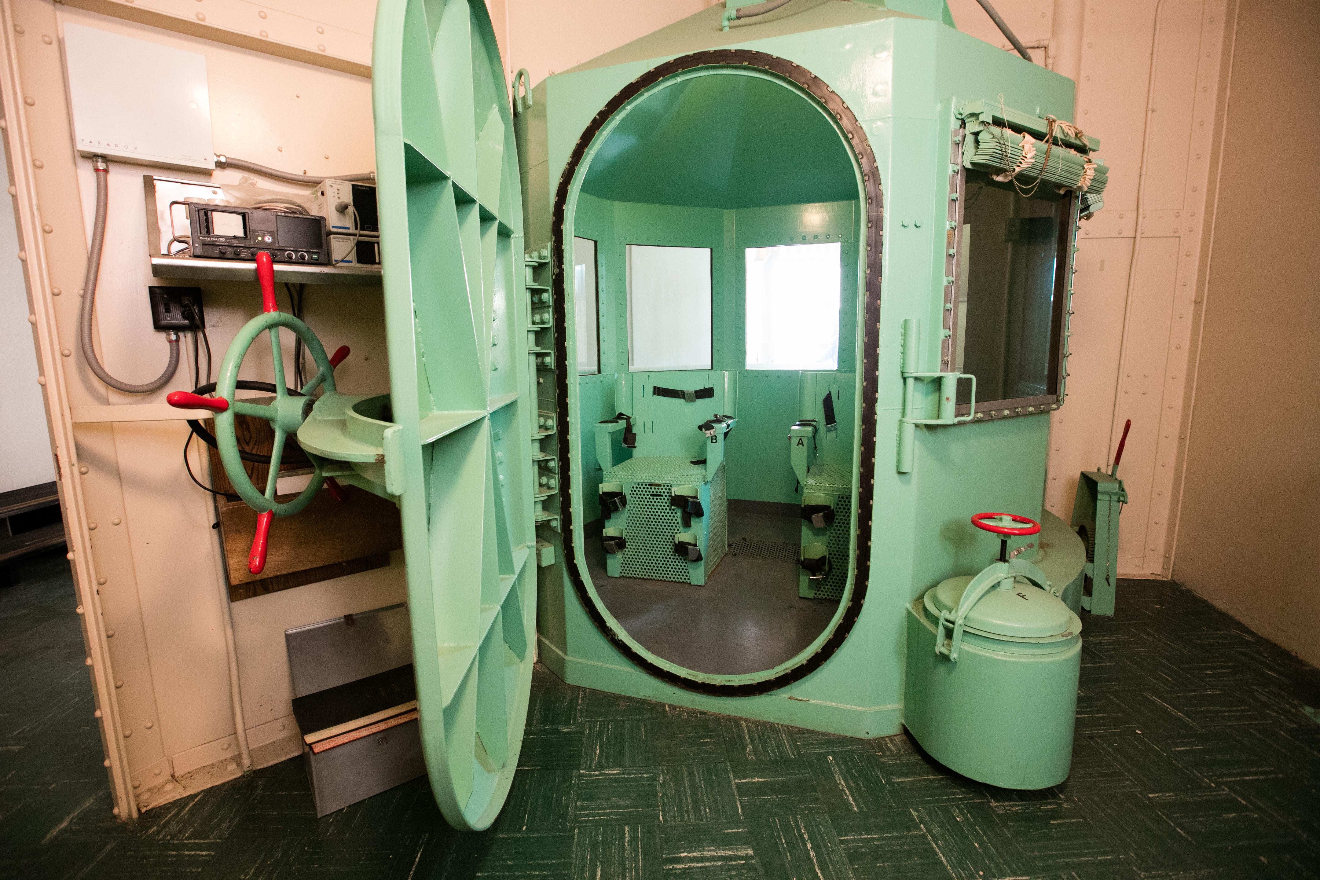 A teal gas chamber with the door open and a big handle like an old-timey safe. 
