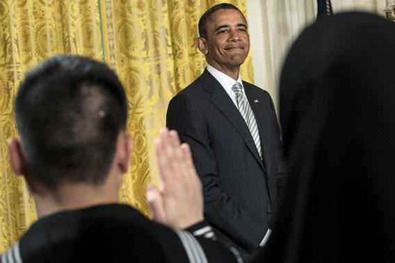 President Obama listens while the oath of allegiance is administered during a naturalization ceremony in the East Room of the White House on March 25, 2013 in Washington.