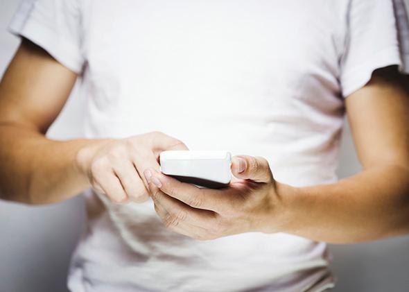 Man in white t-shirt using mobile smart phone
