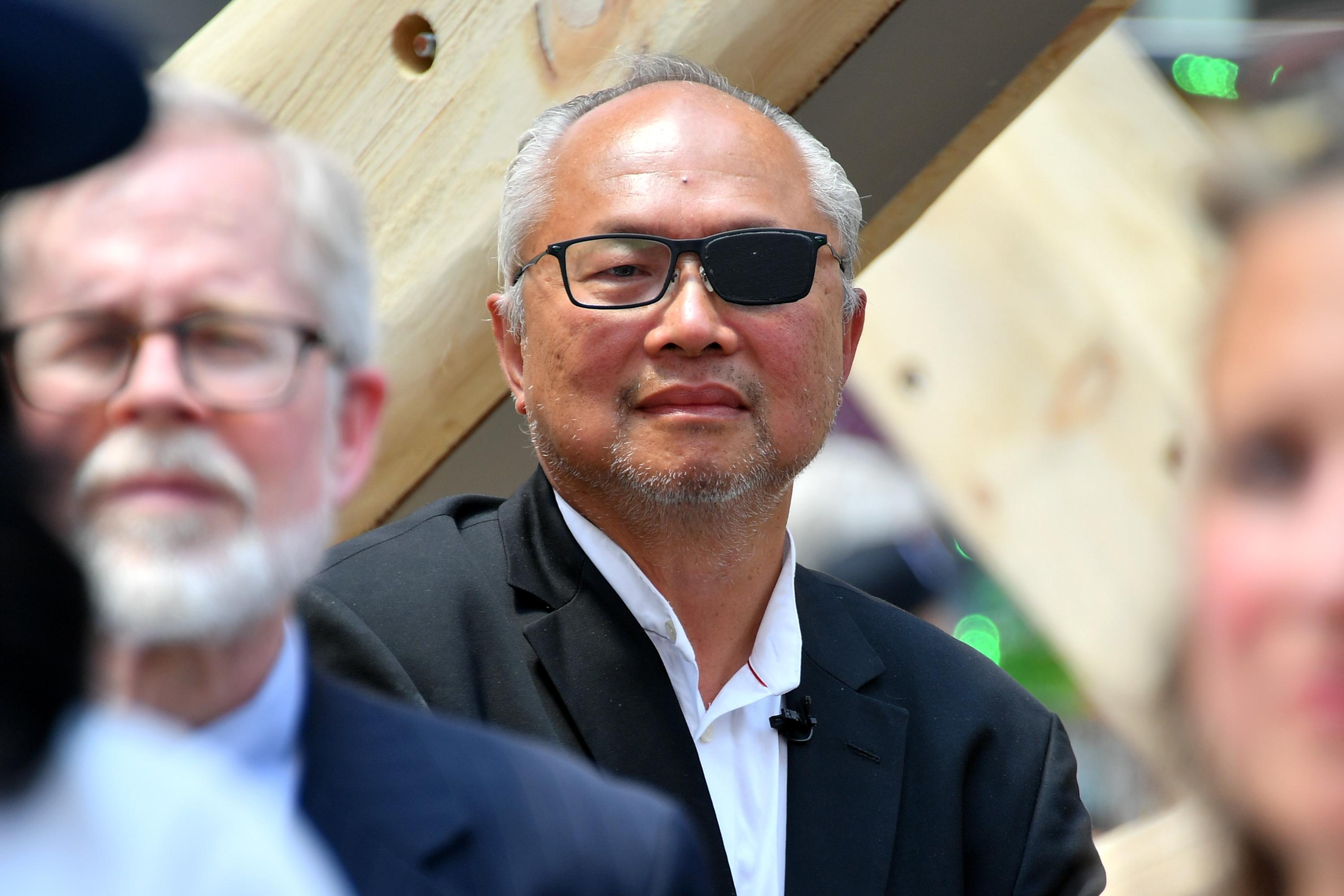 A man with very short white hair, wearing glasses in which one lens is completely blacked out.