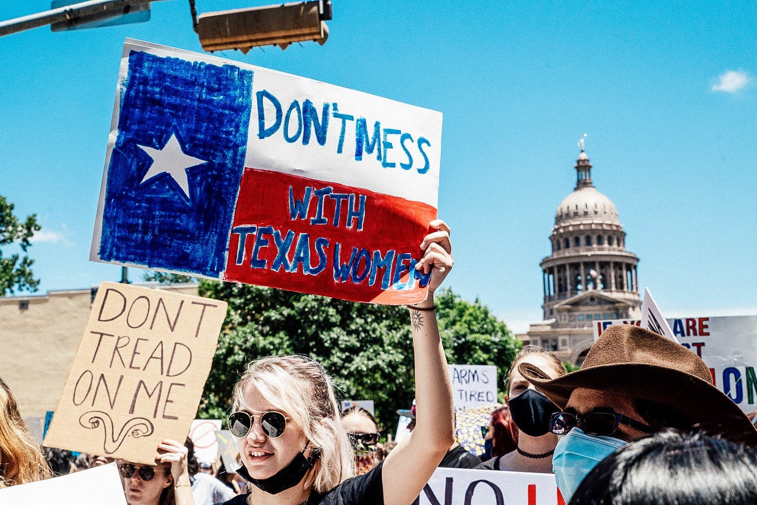 Protesters march in front of the Texas State Capitol holding up signs that say "Don't mess with Texas women" and "Don't tread on me"