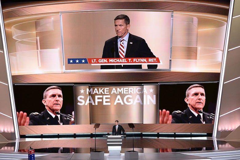 Flynn stands at a lectern as the words MAKE AMERICA SAFE AGAIN and several large images of his face are projected on the huge screen behind him.